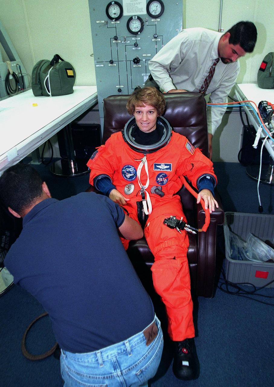 In the Operations and Checkout Building, STS-93 Commander Eileen M. Collins gets help donning her launch and entry suit. After Space Shuttle Columbia's July 20 launch attempt was scrubbed at the T-7 second mark in the countdown, the launch was rescheduled for Thursday, July 22, at 12:28 a.m. EDT. The target landing date is July 26, 1999, at 11:24 p.m. EDT. STS-93 is a five-day mission primarily to release the Chandra X-ray Observatory, which will allow scientists from around the world to study some of the most distant, powerful and dynamic objects in the universe. The new telescope is 20 to 50 times more sensitive than any previous X-ray telescope and is expected unlock the secrets of supernovae, quasars and black holes. The STS-93 crew numbers five: Commander Collins, Pilot Jeffrey S. Ashby, and Mission Specialists Stephen A. Hawley (Ph.D.), Catherine G. Coleman (Ph.D.) and Michel Tognini of France, with the Centre National d'Etudes Spatiales (CNES). Collins is the first woman to serve as commander of a shuttle mission