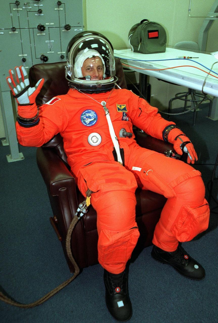 In the Operations and Checkout Building, STS-93 Mission Specialist Michel Tognini of France, who represents the Centre National d'Etudes Spatiales (CNES), waves after donning his launch and entry suit during final launch preparations for the second time. After Space Shuttle Columbia's July 20 launch attempt was scrubbed at the T-7 second mark in the countdown, the launch was rescheduled for Thursday, July 22, at 12:28 a.m. EDT. The target landing date is July 26, 1999, at 11:24 p.m. EDT. STS-93 is a five-day mission primarily to release the Chandra X-ray Observatory, which will allow scientists from around the world to study some of the most distant, powerful and dynamic objects in the universe. The new telescope is 20 to 50 times more sensitive than any previous X-ray telescope and is expected unlock the secrets of supernovae, quasars and black holes. The STS-93 crew numbers five: Commander Eileen M. Collins, Pilot Jeffrey S. Ashby, and Mission Specialists Stephen A. Hawley (Ph.D.), Catherine G. Coleman (Ph.D.) and Tognini. Collins is the first woman to serve as commander of a shuttle mission