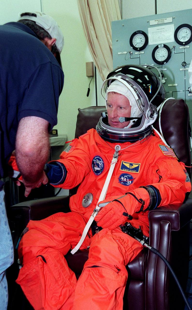 During final launch preparations in the Operations and Checkout Building, STS-93 Mission Specialist Steven A. Hawley (Ph.D.)gets help donning his launch and entry suit from a suit tech. After Space Shuttle Columbia's July 20 launch attempt was scrubbed at the T-7 second mark in the countdown, the launch was rescheduled for Thursday, July 22, at 12:28 a.m. EDT. The target landing date is July 26, 1999, at 11:24 p.m. EDT. STS-93 is a five-day mission primarily to release the Chandra X-ray Observatory, which will allow scientists from around the world to study some of the most distant, powerful and dynamic objects in the universe. The new telescope is 20 to 50 times more sensitive than any previous X-ray telescope and is expected unlock the secrets of supernovae, quasars and black holes. The STS-93 crew numbers five: Commander Eileen M. Collins, Pilot Jeffrey S. Ashby, and Mission Specialists Hawley, Catherine G. Coleman (Ph.D.) and Michel Tognini of France, with the Centre National d'Etudes Spatiales (CNES). Collins is the first woman to serve as commander of a shuttle mission