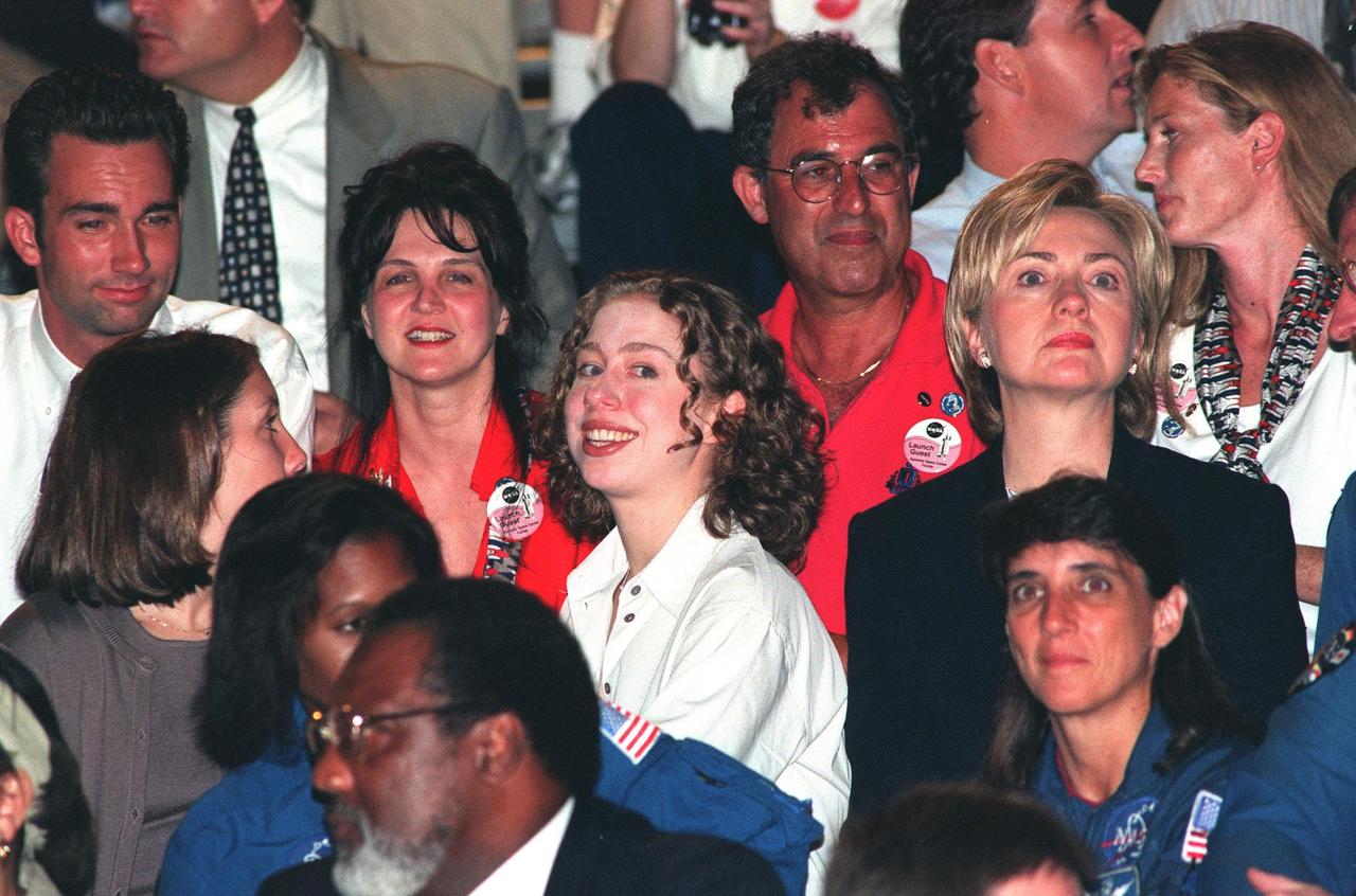 From their seats in the Banana Creek viewing site, First Lady Hillary Rodham Clinton (center, right) and her daughter, Chelsea (next to her at left) eagerly await the second launch attempt of STS-93. Moments before the first scheduled launch, July 20, STS-93 was scrubbed at the T-7 second mark in the countdown due to an indication of a high concentration of hydrogen in an aft engine compartment. The reading proved to be a false alarm. The launch was rescheduled for July 22 at 12:28 a.m. Much attention has been generated over STS-93 due to Commander Eileen M. Collins, the first woman to serve as commander of a Shuttle mission. The primary payload of the five-day mission is the Chandra X-ray Observatory, which will allow scientists from around the world to study some of the most distant, powerful and dynamic objects in the universe