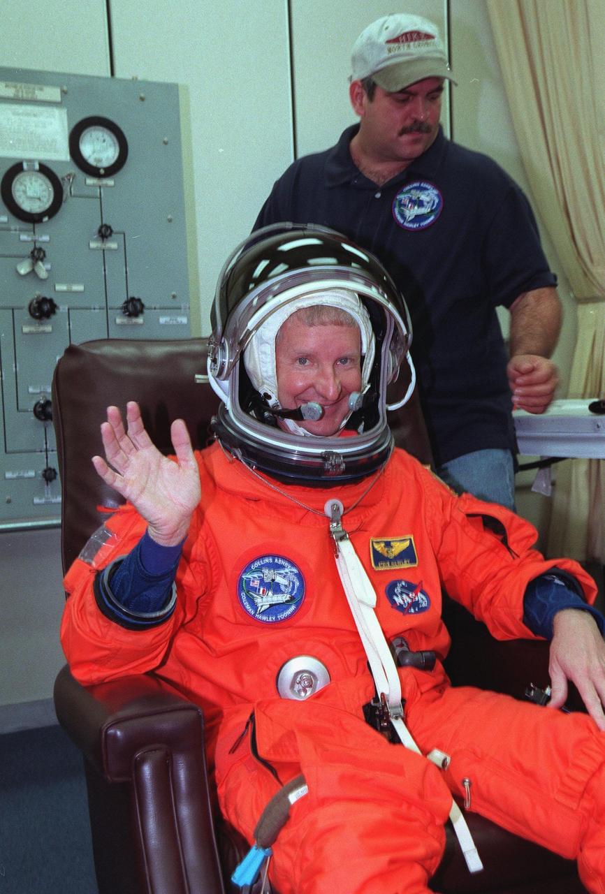 For the third time, during final launch preparations in the Operations and Checkout Building, STS-93 Mission Specialist Steven A. Hawley (Ph.D.) waves after donning his launch and entry suit. After Space Shuttle Columbia's July 20 and 22 launch attempts were scrubbed, the launch was again rescheduled for Friday, July 23, at 12:24 a.m. EDT. STS-93 is a five-day mission primarily to release the Chandra X-ray Observatory, which will allow scientists from around the world to study some of the most distant, powerful and dynamic objects in the universe. The STS-93 crew numbers five: Commander Eileen M. Collins, Pilot Jeffrey S. Ashby, and Mission Specialists Hawley, Catherine G. Coleman (Ph.D.) and Michel Tognini of France, with the Centre National d'Etudes Spatiales (CNES). Collins is the first woman to serve as commander of a shuttle mission