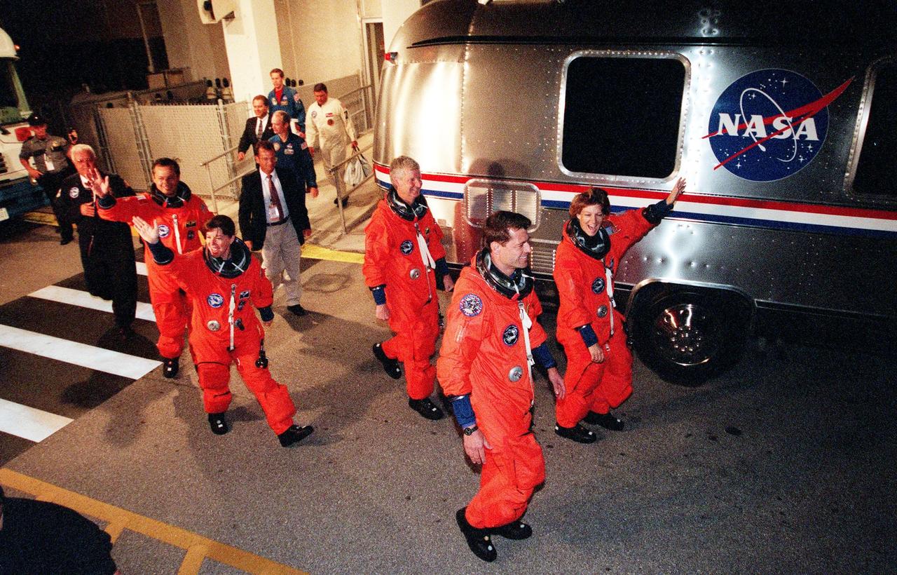 The STS-93 crew wave and cheer as they head for the "Astrovan" a third time to take them to Launch Pad 39-B and liftoff of Space Shuttle Columbia. In their orange launch and entry suits, they are (starting at rear, left to right) Mission Specialists Michel Tognini of France, who represents the Centre National d'Etudes Spatiales (CNES), Catherine G. Coleman (Ph.D.), and Steven A. Hawley (Ph.D.); Pilot Jeffrey S. Ashby; and Commander Eileen M. Collins. After Space Shuttle Columbia's July 20 and 22 launch attempts were scrubbed, the launch was again rescheduled for Friday, July 23, at 12:24 a.m. EDT. The target landing date is July 27 at 11:20 p.m. EDT. STS-93 is a five-day mission primarily to release the Chandra X-ray Observatory, which will allow scientists from around the world to study some of the most distant, powerful and dynamic objects in the universe. Collins is the first woman to serve as commander of a Shuttle mission