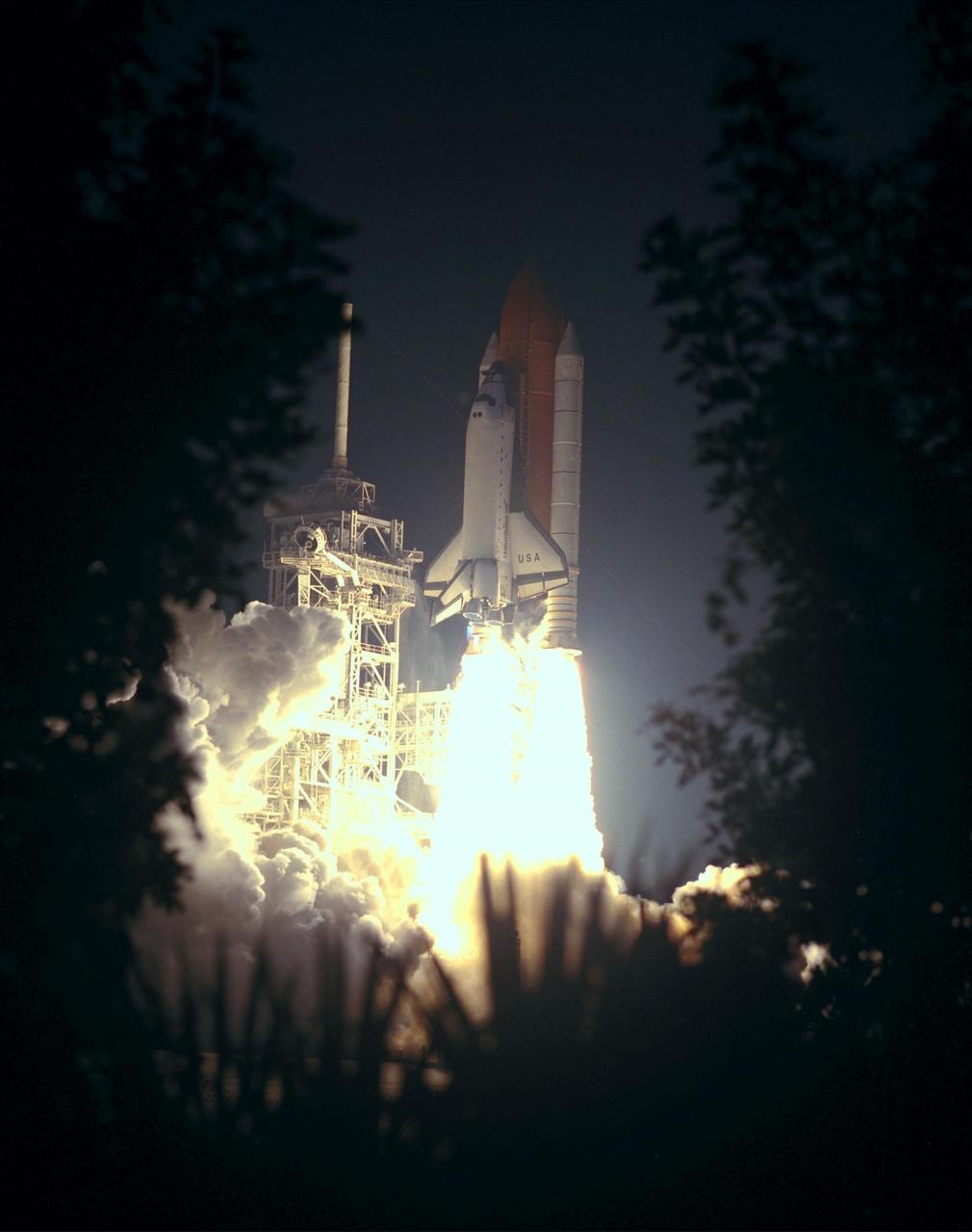 KENNEDY SPACE CENTER, FLA. -- Shrubbery and palmettos frame the fiery launch of Space Shuttle Columbia at 12:31 a.m. EDT. STS-93 is a five-day mission primarily to release the Chandra X-ray Observatory, which will allow scientists from around the world to study some of the most distant, powerful and dynamic objects in the universe. The crew numbers five: Commander Eileen M. Collins, Pilot Jeffrey S. Ashby, and Mission Specialists Steven A. Hawley (Ph.D.), Catherine G. Coleman (Ph.D.) and Michel Tognini of France, with the Centre National d'Etudes Spatiales (CNES). Collins is the first woman to serve as commander of a Shuttle mission. The target landing date is July 27, 1999, at 11:20 p.m. EDT