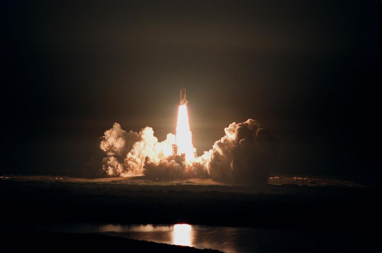KENNEDY SPACE CENTER, FLA. -- The fiery launch of Space Shuttle Columbia is reflected in the water near the Launch Complex . After two unsuccessful attempts on previous nights, liftoff occurred at 12:31 a.m. EDT. STS-93 is a five-day mission primarily to release the Chandra X-ray Observatory, which will allow scientists from around the world to study some of the most distant, powerful and dynamic objects in the universe. The crew numbers five: Commander Eileen M. Collins, Pilot Jeffrey S. Ashby, and Mission Specialists Steven A. Hawley (Ph.D.), Catherine G. Coleman (Ph.D.) and Michel Tognini of France, with the Centre National d'Etudes Spatiales (CNES). The target landing date is July 27, 1999, at 11:20 p.m. EDT
