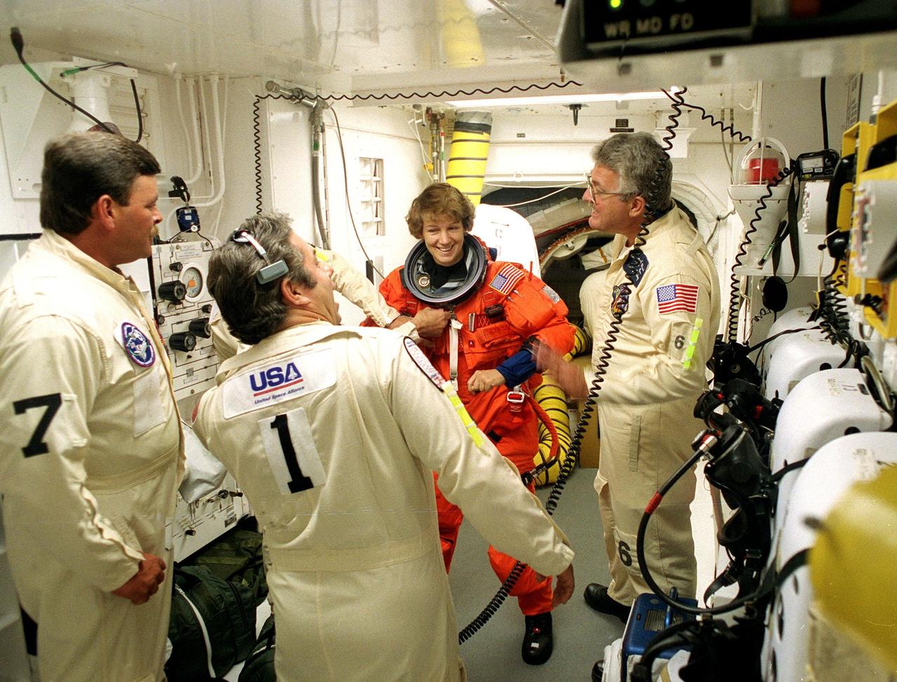 STS-93 Commander Eileen M. Collins is checked out by white room closeout crew members before entering the orbiter Columbia. The white room is an environmental chamber at the end of the orbiter access arm that provides entry to the orbiter crew compartment. STS-93 is a five-day mission primarily to release the Chandra X-ray Observatory, which will allow scientists from around the world to study some of the most distant, powerful and dynamic objects in the universe. After Space Shuttle Columbia's July 20 and 22 launch attempts were scrubbed, the launch was again rescheduled for Friday, July 23, at 12:24 a.m. EDT. The target landing date is July 27 at 11:20 p.m. EDT