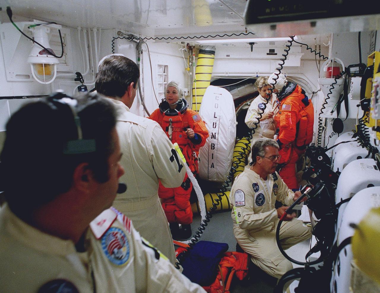 STS-93 Mission Specialist Catherine G. Coleman (Ph.D.) (left) and Pilot Jeffrey S. Ashby (right) are checked out by white room closeout crew members before entering the orbiter Columbia. The white room is an environmental chamber at the end of the orbiter access arm that provides entry to the orbiter crew compartment. STS-93 is a five-day mission primarily to release the Chandra X-ray Observatory, which will allow scientists from around the world to study some of the most distant, powerful and dynamic objects in the universe. After Space Shuttle Columbia's July 20 and 22 launch attempts were scrubbed, the launch was again rescheduled for Friday, July 23, at 12:24 a.m. EDT. The target landing date is July 27 at 11:20 p.m. EDT