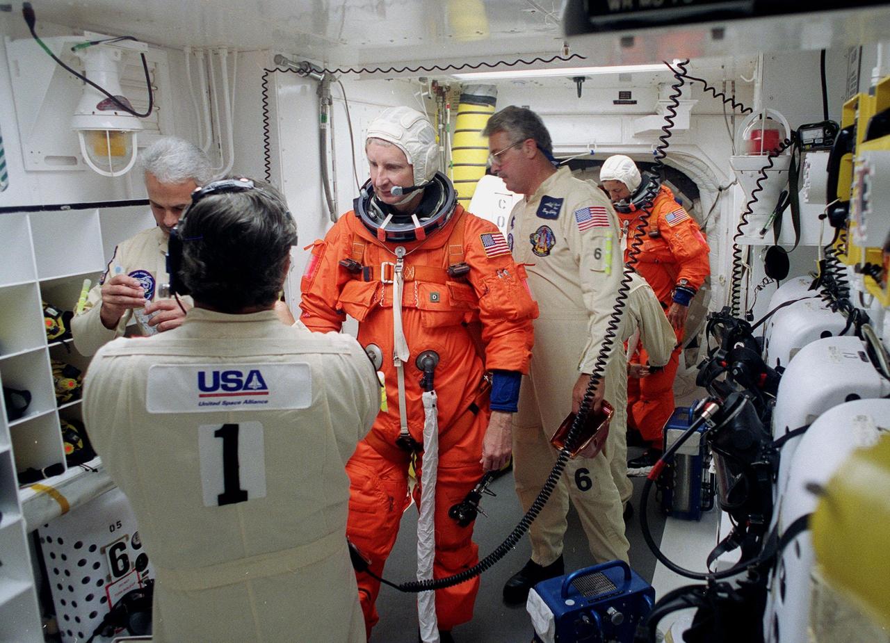 STS-93 Mission Specialist Steven A. Hawley (Ph.D.) is checked out by white room closeout crew members before entering the orbiter Columbia. In the background is Mission Specialist Michel Tognini of France, waiting to enter Columbia. The white room is an environmental chamber at the end of the orbiter access arm that provides entry to the orbiter crew compartment. STS-93 is a five-day mission primarily to release the Chandra X-ray Observatory, which will allow scientists from around the world to study some of the most distant, powerful and dynamic objects in the universe. After Space Shuttle Columbia's July 20 and 22 launch attempts were scrubbed, the launch was again rescheduled for Friday, July 23, at 12:24 a.m. EDT. The target landing date is July 27 at 11:20 p.m. EDT