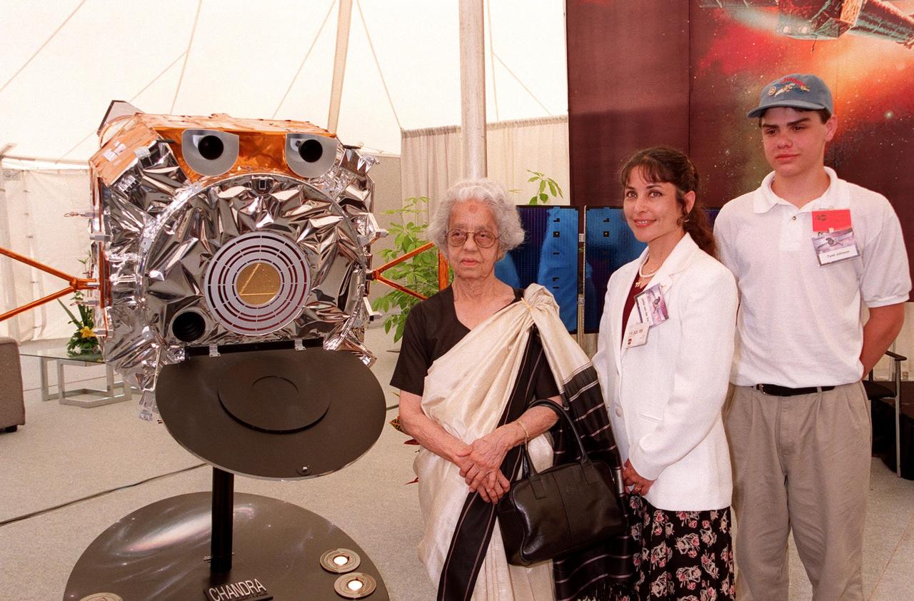 KENNEDY SPACE CENTER, FLA. -- Mrs. Lalitha Chandrasekhar (left), wife of the late Indian-American Nobel Laureate Subrahmanyan Chandrasekhar, poses with a model of the Chandra X-ray Observatory and the winners of the contest to rename the telescope in the TRW Media Hospitality Tent at the NASA Press Site at KSC. The winners of the contest are Jatila van der Veen (center), academic coordinator and lecturer, Physics Dept., University of Santa Barbara, Calif., and Tyrel Johnson (right), high school student, Laclede, Idaho. The name "Chandra," a shortened version of Chandrasekhar's name which he preferred among friends and colleagues, was chosen to honor the Nobel Laureate. "Chandra" also means "Moon" or "luminous" in Sanskrit. The observatory is scheduled to be launched aboard Columbia on Space Shuttle mission STS-93