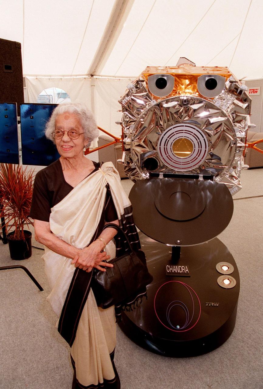 KENNEDY SPACE CENTER, FLA. -- Mrs. Lalitha Chandrasekhar, wife of the late Indian-American Nobel Laureate Subrahmanyan Chandrasekhar, poses with a model of the Chandra X-ray Observatory in the TRW Media Hospitality Tent at the NASA Press Site at KSC. The name "Chandra," a shortened version of Chandrasekhar's name which he preferred among friends and colleagues, was chosen in a contest to rename the telescope. "Chandra" also means "Moon" or "luminous" in Sanskrit. The observatory is scheduled to be launched aboard Columbia on Space Shuttle mission STS-93