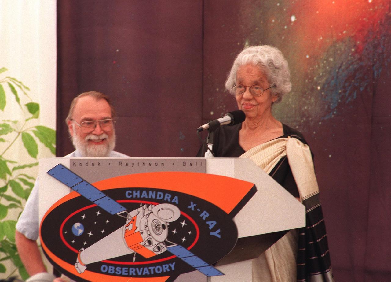 KENNEDY SPACE CENTER, FLA. -- Mrs. Lalitha Chandrasekhar (right), wife of the late Indian-American Nobel Laureate Subrahmanyan Chandrasekhar, addresses the media and other invited guests in the TRW Media Hospitality Tent at the NASA Press Site at KSC as Dr. Alan Bunner, Science Program Director, Structure and Evolution of the Universe, Office of Space Science, NASA Headquarters, Washington, D.C., looks on. The name "Chandra," a shortened version of her husband's name which he preferred among friends and colleagues, was chosen in a contest to rename the Advanced X-ray Astrophysics Facility. "Chandra" also means "Moon" or "luminous" in Sanskrit. The observatory is scheduled to be launched aboard Columbia on Space Shuttle mission STS-93