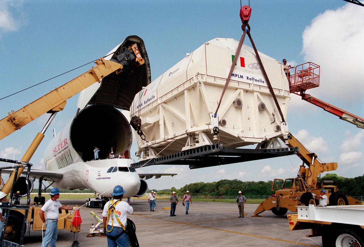 KENNEDY SPACE CENTER, FLA. -- Under clear and cloud-spotted skies at the Shuttle Landing Facility, cranes support the Multi-Purpose Logistics Module (MPLM) called Raffaello after the "Beluga" Super Transporter (left) has rolled away from it. Raffaello will be transferred to the Space Station Processing Facility for testing, joining the first Italian-built MPLM, Leonardo. One of Italy's major contributions to the ISS program, the MPLM is a reusable logistics carrier and the primary delivery system used to resupply and return station cargo requiring a pressurized environment. Weighing nearly 4.5 tons, the module measures 21 feet long and 15 feet in diameter. Raffaello is scheduled to be launched on mission STS-100 July 27, 2000