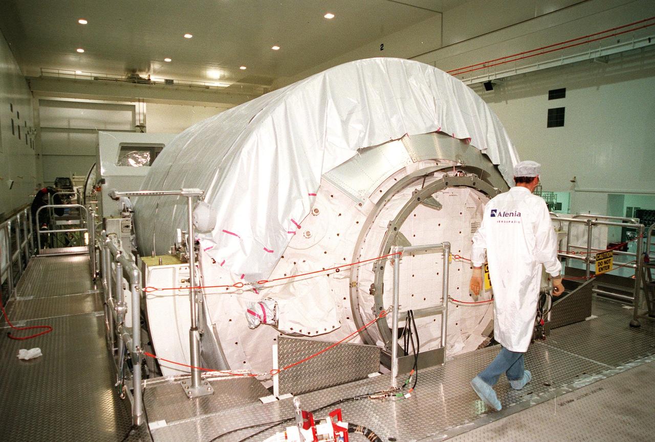 KENNEDY SPACE CENTER, FLA. -- The Multi-Purpose Logistics Module (MPLM) called Raffaello rests in its workstand in the Space Station Processing Facility (SSPF) as an Alenia Aerospazio worker passes by. The Italian aerospace company will provide engineering support for Raffaello, along with NASA, Boeing and the Italian Space Agency. One of Italy's major contributions to the ISS program, the MPLM is a reusable logistics carrier and the primary delivery system used to resupply and return station cargo requiring a pressurized environment. Weighing nearly 4.5 tons, the Raffaello measures 21 feet long and 15 feet in diameter. Raffaello will undergo testing. joining the first Italian-built MPLM, Leonardo, also in the SSPF. Raffaello is scheduled to be launched on mission STS-100 on July 27, 2000
