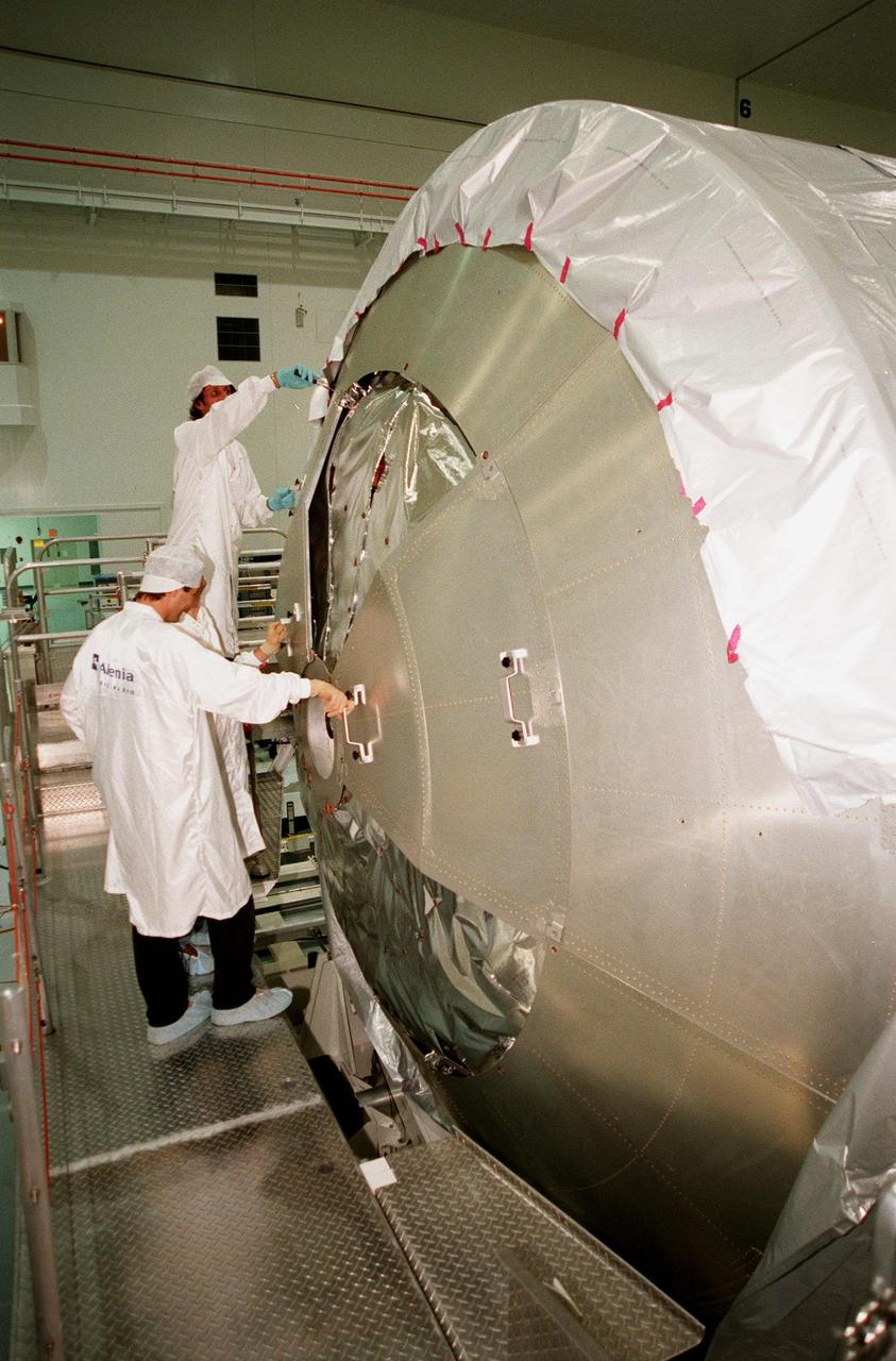 KENNEDY SPACE CENTER, FLA. -- In the Space Station Processing Facility (SSPF), workers from the Italian aerospace company Alenia Aerospazio begin removing the protective cover from the Multi-Purpose Logistics Module (MPLM) called Raffaello. The Italian aerospace company will provide engineering support for Raffaello, along with NASA, Boeing and the Italian Space Agency. One of Italy's major contributions to the ISS program, the MPLM is a reusable logistics carrier and the primary delivery system used to resupply and return station cargo requiring a pressurized environment. Weighing nearly 4.5 tons, the Raffaello measures 21 feet long and 15 feet in diameter. Raffaello will undergo testing. joining the first Italian-built MPLM, Leonardo, also in the SSPF. Raffaello is scheduled to be launched on mission STS-100 on July 27, 2000