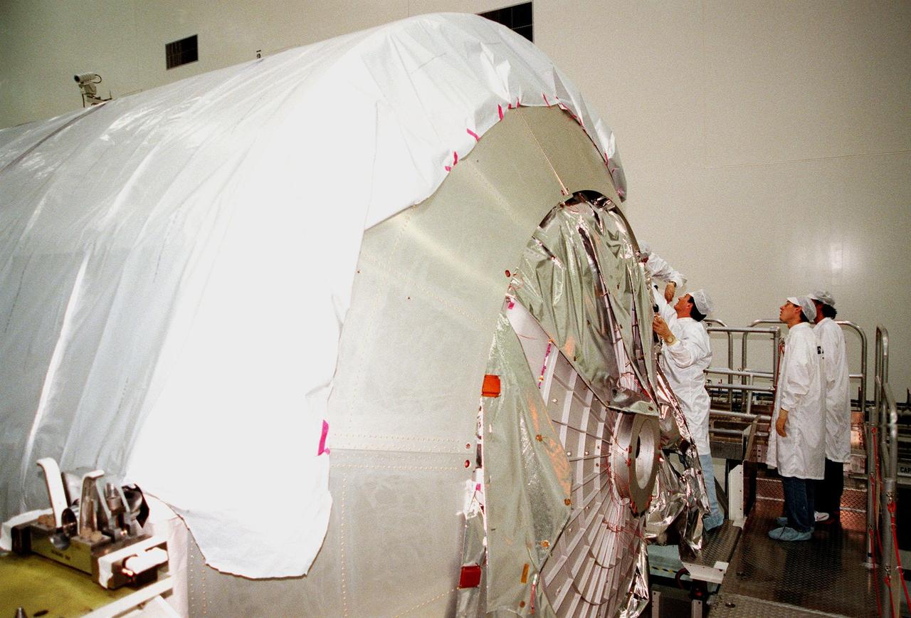KENNEDY SPACE CENTER, FLA. -- In the Space Station Processing Facility (SSPF), workers from the Italian aerospace company Alenia Aerospazio begin removing the protective cover from the Multi-Purpose Logistics Module (MPLM) called Raffaello. The Italian aerospace company will provide engineering support for Raffaello, along with NASA, Boeing and the Italian Space Agency. One of Italy's major contributions to the ISS program, the MPLM is a reusable logistics carrier and the primary delivery system used to resupply and return station cargo requiring a pressurized environment. Weighing nearly 4.5 tons, the Raffaello measures 21 feet long and 15 feet in diameter. Raffaello will undergo testing. joining the first Italian-built MPLM, Leonardo, also in the SSPF. Raffaello is scheduled to be launched on mission STS-100 on July 27, 2000