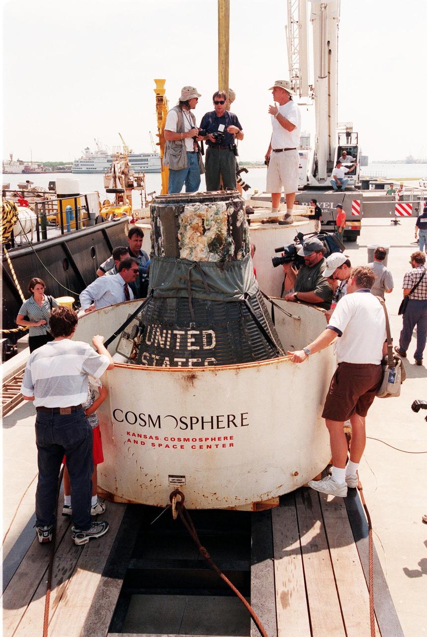 KENNEDY SPACE CENTER, FLA. -- Media and photographers get a close-up view of the Liberty Bell 7 Project Mercury capsule after its recovery from the Atlantic Ocean floor where it lay for 38 years.   Launched July 21, 1961, the capsule made a successful 16-minute suborbital flight, with astronaut Virgil "Gus" Grissom aboard, and splashed down in the Atlantic Ocean.  A prematurely jettisoned hatch caused the capsule to flood and a Marine rescue helicopter was unable to lift it.  It quickly sank to a three-mile depth.  Grissom was rescued but his spacecraft remained lost on the ocean floor, until now. Curt Newport, an underwater salvage expert, located the capsule through modern technology, and after one abortive attempt, successfully raised it and brought it to Port Canaveral. The recovery of Liberty Bell 7 fulfilled a 14-year dream for the expedition leader.  The expedition was sponsored by the Discovery Channel.  The capsule is being moved to the Kansas Cosmosphere and Space Center in Hutchinson, Kansas,  where it will be restored for eventual public display. Newport has also been involved in salvage operations of the Space Shuttle Challenger and TWA Flight 800 that crashed off the coast of Long Island, N.Y.