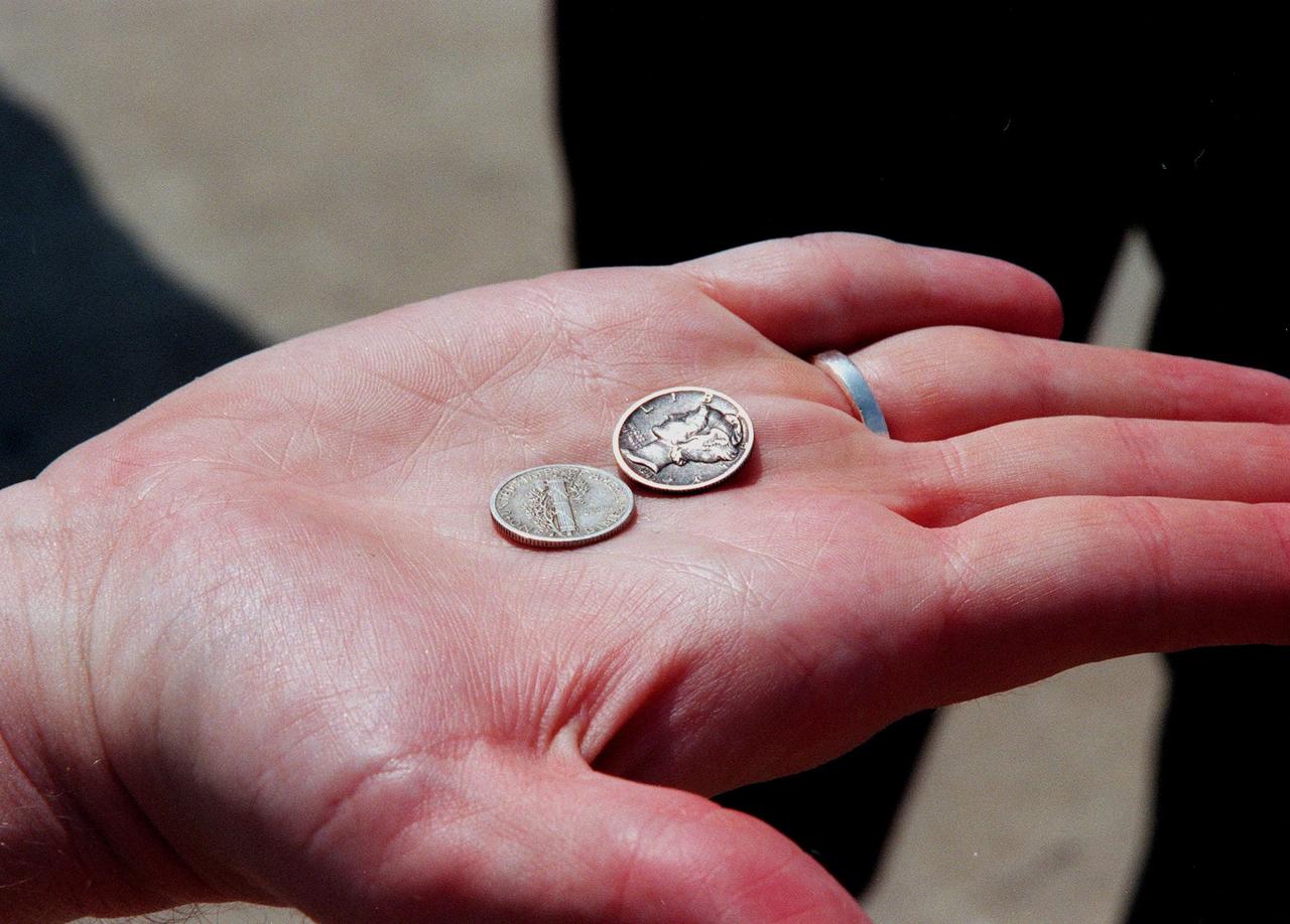 KENNEDY SPACE CENTER, FLA. -- This photograph shows two mercury dimes that were found inside the recently recovered Liberty Bell 7 Project Mercury capsule. Thirty-eight years ago, the capsule made a successful 16-minute suborbital flight, with astronaut Virgil "Gus" Grissom aboard, and splashed down in the Atlantic Ocean.  A prematurely jettisoned hatch caused the capsule to flood and a Marine rescue helicopter was unable to lift it.  It quickly sank to a three-mile depth.  Grissom was rescued but his spacecraft remained lost on the ocean floor, until now. In an expedition sponsored by the Discovery Channel, underwater salvage expert Curt Newport fulfilled a 14-year dream in finding and, after one abortive attempt, successfully raising the capsule and bringing it to Port Canaveral.  The dimes had apparently been placed in the capsule before its launch July 21, 1961. The capsule is being moved to the Kansas Cosmosphere and Space Center in Hutchinson, Kansas,  where it will be restored for eventual public display. Newport has also been involved in salvage operations of the Space Shuttle Challenger and TWA Flight 800 that crashed off the coast of Long Island, N.Y.