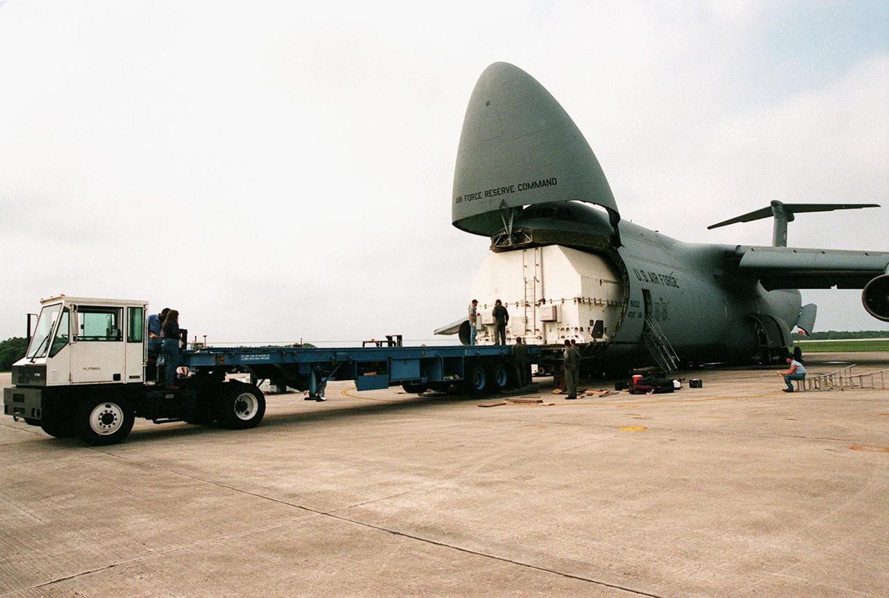 A shipping container with payload flight hardware for the Third Hubble Space Telescope Servicing Mission (SM-3A) is ready for transfer onto a transporter from the C-5 air cargo plane that brought it to KSC. The hardware will be taken to the Payload Hazardous Servicing Facility for final testing and integration of payload elements. Mission STS-103 is a "call-up" mission which is being planned due to the need to replace portions of the Hubble's pointing system, the gyros, which have begun to fail. Although Hubble is operating normally and conducting its scientific observations, only three of its six gyroscopes are working properly. The gyroscopes allow the telescope to point at stars, galaxies and planets. The STS-103 crew will not only replace gyroscopes, it will also replace a Fine Guidance Sensor and an older computer with a new enhanced model, an older data tape recorder with a solid state digital recorder, a failed spare transmitter with a new one, and degraded insulation on the telescope with new thermal insulation. The crew will also install a Battery Voltage/Temperature Improvement Kit to protect the spacecraft batteries from overcharging and overheating when the telescope goes into a safe mode. Launch of STS-93 is currently targeted for Oct. 14 but under review, pending the launch date of a prior mission, STS-99, also under review
