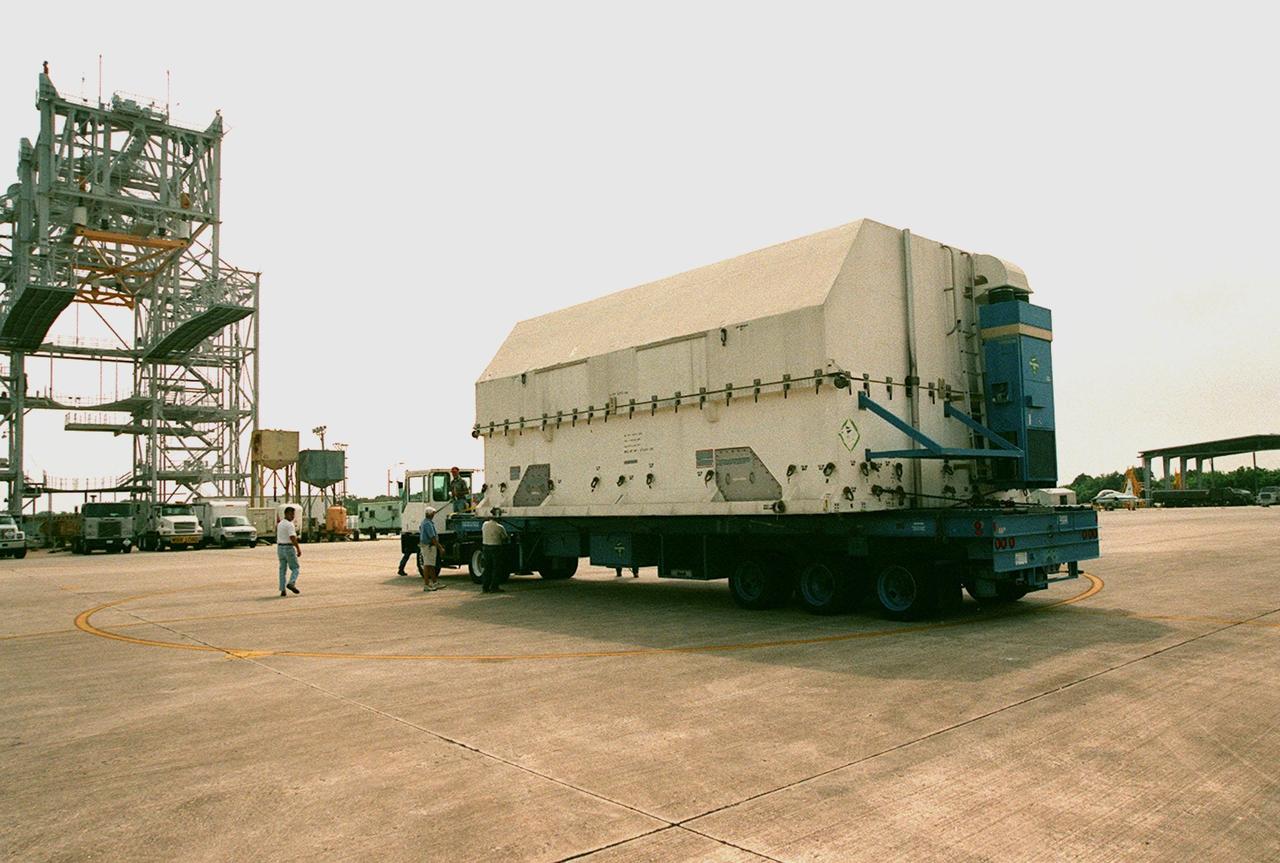 A shipping container with payload flight hardware for the Third Hubble Space Telescope Servicing Mission (SM-3A) sits on a flatbed trailer for transfer to the Payload Hazardous Servicing Facility where it will undergo final testing and integration of payload elements. Mission STS-103 is a "call-up" mission which is being planned due to the need to replace portions of the Hubble's pointing system, the gyros, which have begun to fail. Although Hubble is operating normally and conducting its scientific observations, only three of its six gyroscopes are working properly. The gyroscopes allow the telescope to point at stars, galaxies and planets. The STS-103 crew will not only replace gyroscopes, it will also replace a Fine Guidance Sensor and an older computer with a new enhanced model, an older data tape recorder with a solid state digital recorder, a failed spare transmitter with a new one, and degraded insulation on the telescope with new thermal insulation. The crew will also install a Battery Voltage/Temperature Improvement Kit to protect the spacecraft batteries from overcharging and overheating when the telescope goes into a safe mode. Launch of STS-93 is currently targeted for Oct. 14 but under review, pending the launch date of a prior mission, STS-99, also under review