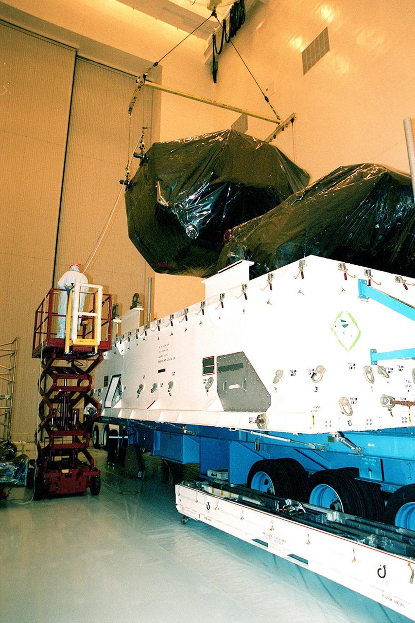 In the Payload Hazardous Servicing Facility (PHSF), a crane lifts equipment for mission STS-103 out of its shipping container. The equipment is the first part of payload flight hardware for the third Hubble Space Telescope Servicing Mission (SM-3A). The hardware will undergo final testing and integration of payload elements in the PHSF. Mission STS-103 is a "call-up" mission which is being planned due to the need to replace portions of the Hubble's pointing system, the gyros, which have begun to fail. Although Hubble is operating normally and conducting its scientific observations, only three of its six gyroscopes are working properly. The gyroscopes allow the telescope to point at stars, galaxies and planets. The STS-103 crew will not only replace gyroscopes, it will also replace a Fine Guidance Sensor and an older computer with a new enhanced model, an older data tape recorder with a solid state digital recorder, a failed spare transmitter with a new one, and degraded insulation on the telescope with new thermal insulation. The crew will also install a Battery Voltage/Temperature Improvement Kit to protect the spacecraft batteries from overcharging and overheating when the telescope goes into a safe mode. Launch of STS-103 is currently targeted for Oct. 14 but the date is under review