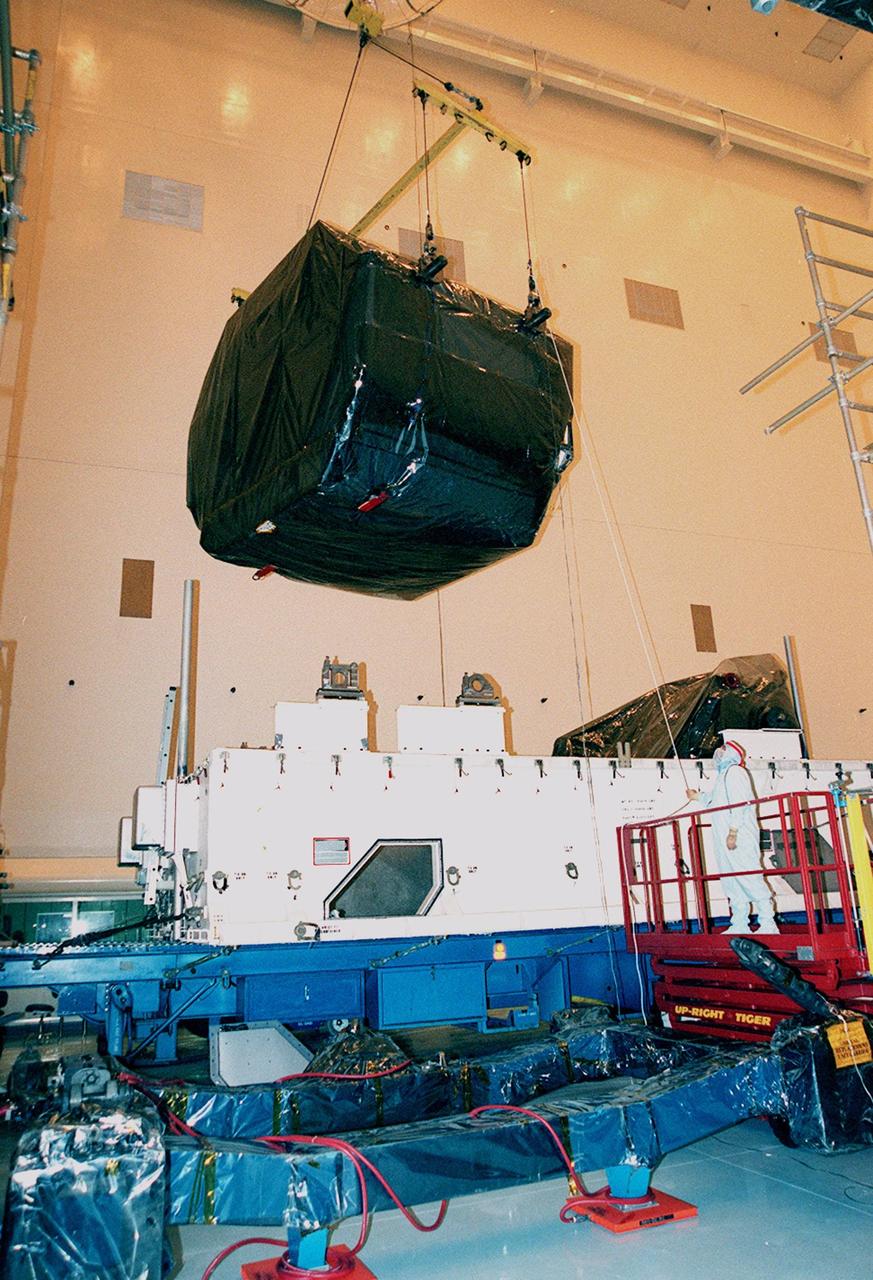 In the Payload Hazardous Servicing Facility (PHSF), a crane lifts equipment for mission STS-103 out of its shipping container to move it to a workstand. The equipment is the first part of payload flight hardware for the third Hubble Space Telescope Servicing Mission (SM-3A). The hardware will undergo final testing and integration of payload elements in the PHSF. Mission STS-103 is a "call-up" mission which is being planned due to the need to replace portions of the Hubble's pointing system, the gyros, which have begun to fail. Although Hubble is operating normally and conducting its scientific observations, only three of its six gyroscopes are working properly. The gyroscopes allow the telescope to point at stars, galaxies and planets. The STS-103 crew will not only replace gyroscopes, it will also replace a Fine Guidance Sensor and an older computer with a new enhanced model, an older data tape recorder with a solid state digital recorder, a failed spare transmitter with a new one, and degraded insulation on the telescope with new thermal insulation. The crew will also install a Battery Voltage/Temperature Improvement Kit to protect the spacecraft batteries from overcharging and overheating when the telescope goes into a safe mode. Launch of STS-103 is currently targeted for Oct. 14 but the date is under review