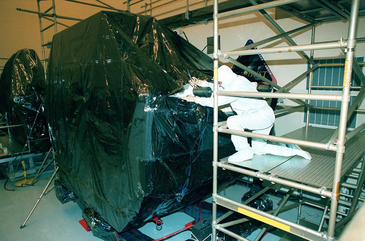 In the Payload Hazardous Servicing Facility (PHSF), a worker begins to open the protective covering over a part of payload flight hardware for the third Hubble Space Telescope Servicing Mission (SM-3A). The hardware will undergo final testing and integration of payload elements in the PHSF. Mission STS-103 is a "call-up" mission which is being planned due to the need to replace portions of the Hubble's pointing system, the gyros, which have begun to fail. Although Hubble is operating normally and conducting its scientific observations, only three of its six gyroscopes are working properly. The gyroscopes allow the telescope to point at stars, galaxies and planets. The STS-103 crew will not only replace gyroscopes, it will also replace a Fine Guidance Sensor and an older computer with a new enhanced model, an older data tape recorder with a solid state digital recorder, a failed spare transmitter with a new one, and degraded insulation on the telescope with new thermal insulation. The crew will also install a Battery Voltage/Temperature Improvement Kit to protect the spacecraft batteries from overcharging and overheating when the telescope goes into a safe mode. Launch of STS-103 is currently targeted for Oct. 14 but the date is under review
