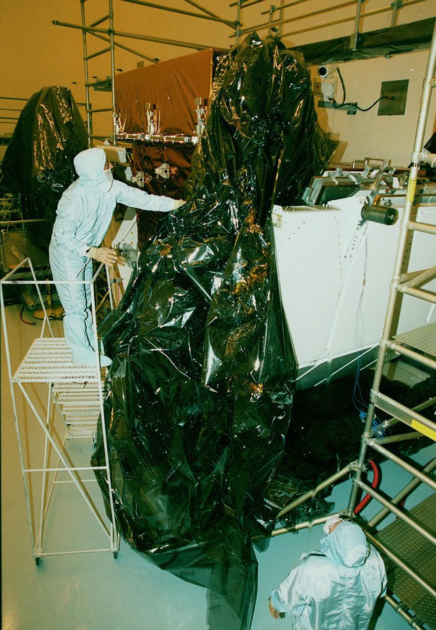 In the Payload Hazardous Servicing Facility (PHSF), workers remove the protective covering from a part of payload flight hardware for the third Hubble Space Telescope Servicing Mission (SM-3A). The hardware will undergo final testing and integration of payload elements in the PHSF. Mission STS-103 is a "call-up" mission which is being planned due to the need to replace portions of the Hubble's pointing system, the gyros, which have begun to fail. Although Hubble is operating normally and conducting its scientific observations, only three of its six gyroscopes are working properly. The gyroscopes allow the telescope to point at stars, galaxies and planets. The STS-103 crew will not only replace gyroscopes, it will also replace a Fine Guidance Sensor and an older computer with a new enhanced model, an older data tape recorder with a solid state digital recorder, a failed spare transmitter with a new one, and degraded insulation on the telescope with new thermal insulation. The crew will also install a Battery Voltage/Temperature Improvement Kit to protect the spacecraft batteries from overcharging and overheating when the telescope goes into a safe mode. Launch of STS-103 is currently targeted for Oct. 14 but the date is under review