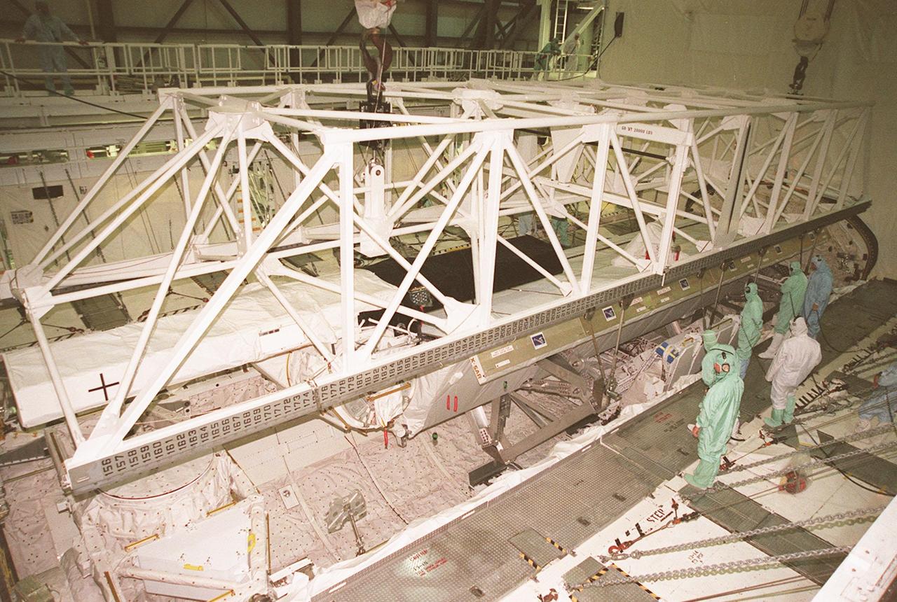 Workers inside orbiter Endeavour's payload bay observe as an overhead crane maneuvers to lift the Shuttle Radar Topography Mission (SRTM) for its transfer out of the orbiter to a payload canister. The payload on mission STS-99, SRTM is being removed to allow technicians access to the orbiter's midbody for planned wiring inspections. Endeavour is in the Orbiter Processing Facility. The entire fleet of orbiters is being inspected for wiring abrasions after the problem was first discovered in Columbia. Shuttle managers are reviewing several manifest options and could establish new target launch dates for the balance of 1999 next week. Shuttle Endeavour currently remains slated for launch in early October