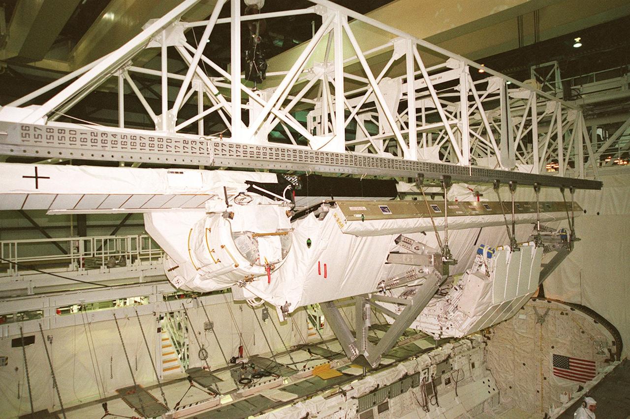 Inside orbiter Endeavour's payload bay, a crane lifts the Shuttle Radar Topography Mission (SRTM) for its transfer out of the orbiter to a payload canister. The payload on mission STS-99, SRTM is being removed to allow technicians access to the orbiter's midbody for planned wiring inspections. Endeavour is in the Orbiter Processing Facility. The entire fleet of orbiters is being inspected for wiring abrasions after the problem was first discovered in Columbia. Shuttle managers are reviewing several manifest options and could establish new target launch dates for the balance of 1999 next week. Shuttle Endeavour currently remains slated for launch in early October