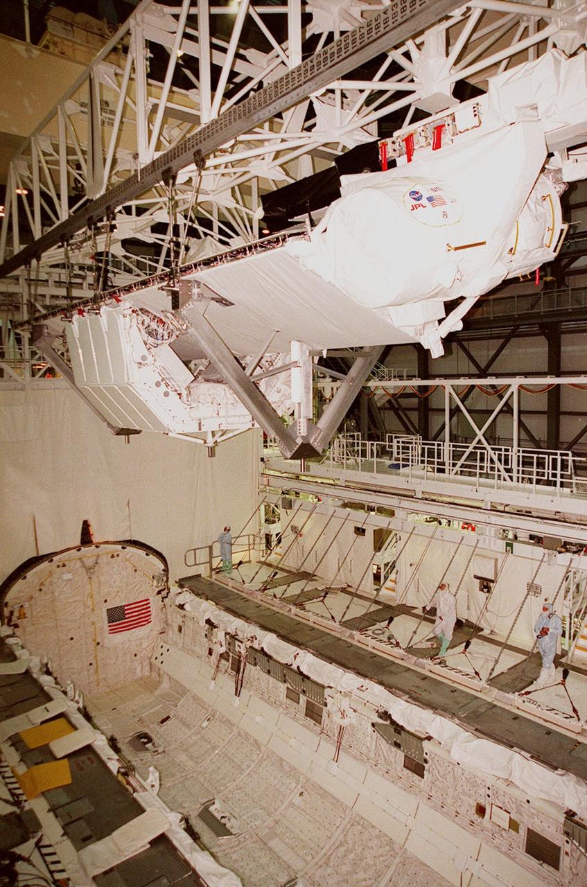 Inside orbiter Endeavour's payload bay, a crane lifts the Shuttle Radar Topography Mission (SRTM) clear of the orbiter for transfer to a payload canister. The payload on mission STS-99, SRTM is being removed to allow technicians access to the orbiter's midbody for planned wiring inspections. Endeavour is in the Orbiter Processing Facility. The entire fleet of orbiters is being inspected for wiring abrasions after the problem was first discovered in Columbia. Shuttle managers are reviewing several manifest options and could establish new target launch dates for the balance of 1999 next week. Shuttle Endeavour currently remains slated for launch in early October