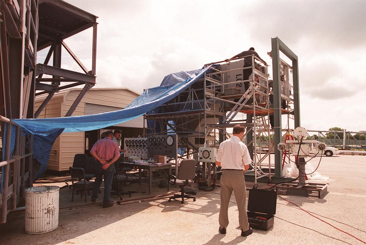 At the Launch Equipment Test Facility, workers check results from testing the X-33 umbilical system. From left are Greg Melton (left), a NASA engineer; Will Reaves, with Lockheed Martin Technical Operations; and Scott Holcomb, also with Lockheed Martin Technical Operations. A team of Kennedy Space Center experts developed the umbilical system, comprising panels, valves and hoses that provide the means to load the X-33 with super-cold propellant. The X-33, under construction at Lockheed Martin Skunk Works in Palmdale, Calif., is a half-scale prototype of the planned operational reusable launch vehicle dubbed VentureStar