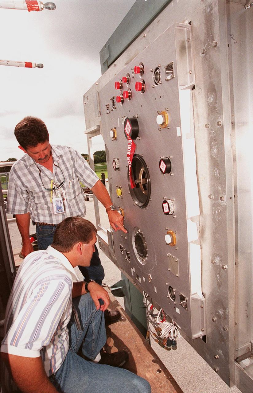 At the Launch Equipment Test Facility, , Will Reaves and Mike Solomon (kneeling), both with Lockheed Martin Technical Operations, observe parts of the X-33 umbilical system during testing. A team of Kennedy Space Center experts developed the umbilical system, comprising panels, valves and hoses that provide the means to load the X-33 with super-cold propellant. The X-33, under construction at Lockheed Martin Skunk Works in Palmdale, Calif., is a half-scale prototype of the planned operational reusable launch vehicle dubbed VentureStar