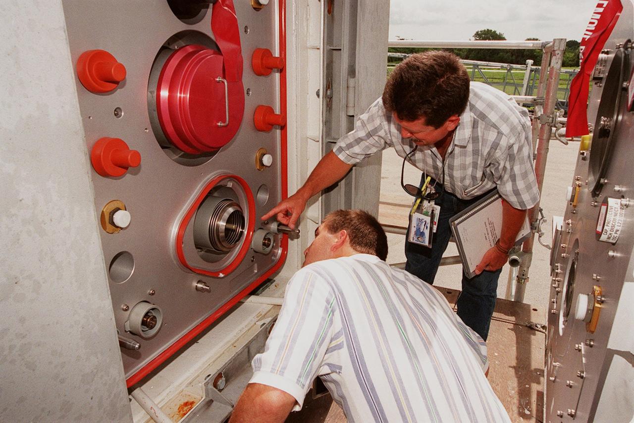 At the Launch Equipment Test Facility, Mike Solomon (left) and Will Reaves (right), both with Lockheed Martin Technical Operations, move in for a close look at part of the X-33 umbilical system. A team of Kennedy Space Center experts developed the umbilical system, comprising panels, valves and hoses that provide the means to load the X-33 with super-cold propellant. The X-33, under construction at Lockheed Martin Skunk Works in Palmdale, Calif., is a half-scale prototype of the planned operational reusable launch vehicle dubbed VentureStar