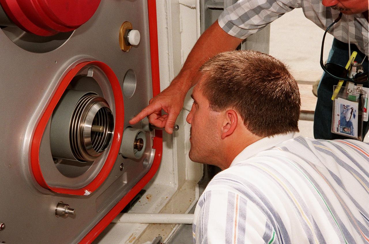 At the Launch Equipment Test Facility, Mike Solomon, with Lockheed Martin Technical Operations, studies a part of the X-33 umbilical system during testing. Pointing to the part is Will Reaves, also with Lockheed Martin Technical Operations. A team of Kennedy Space Center experts developed the umbilical system, comprising panels, valves and hoses that provide the means to load the X-33 with super-cold propellant. The X-33, under construction at Lockheed Martin Skunk Works in Palmdale, Calif., is a half-scale prototype of the planned operational reusable launch vehicle dubbed VentureStar
