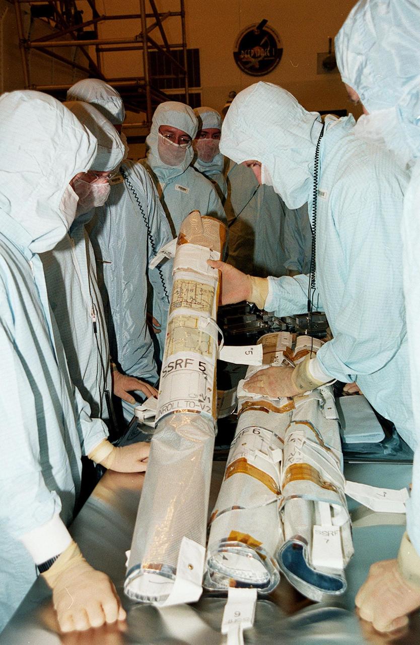 In the Payload Hazardous Servicing Facility, STS-103 Mission Specialist Steven L. Smith (right) and other members of the crew look over new Multi-Layer Insulation (MLI) intended for the Hubble Space Telescope. The seven-member crew, taking part in a Crew Equipment Interface Test, are Commander Curtis L. Brown Jr., Pilot Scott J. Kelly, and Mission Specialists Smith, C. Michael Foale (Ph.D.), John M. Grunsfeld (Ph.D.), Claude Nicollier of Switzerland, and Jean-François Clervoy of France. Nicollier and Clervoy are with the European Space Agency. Mission STS-103 is a "call-up" due to the need to replace portions of the pointing system, the gyros, which have begun to fail on the Hubble Space Telescope. Although Hubble is operating normally and conducting its scientific observations, only three of its six gyroscopes are working properly. The gyroscopes allow the telescope to point at stars, galaxies and planets. The STS-103 crew will not only replace gyroscopes, it will also replace a Fine Guidance Sensor and an older computer with a new enhanced model, an older data tape recorder with a solid state digital recorder, a failed spare transmitter with a new one, and degraded insulation on the telescope with the MLI. The crew will also install a Battery Voltage/Temperature Improvement Kit to protect the spacecraft batteries from overcharging and overheating when the telescope goes into a safe mode. The scheduled launch date in October is under review