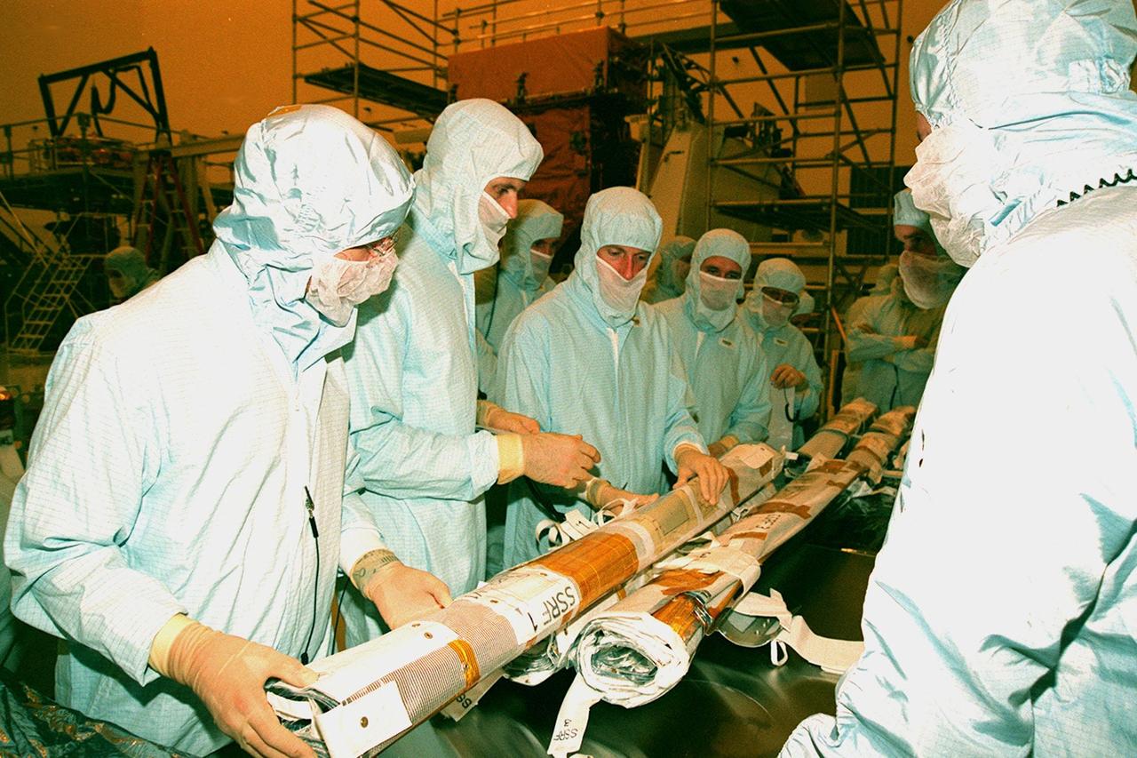 During a Crew Equipment Interface Test, members of the STS-103 crew check out new Multi-Layer Insulation (MLI) for the Hubble Space Telescope. The payload hardware is in the Payload Hazardous Servicing Facility. From left are Mission Specialists Claude Nicollier of Switzerland, Steven L. Smith, C. Michael Foale (Ph.D.), and John M. Grunsfeld (Ph.D.). Other members of the crew are Commander Curtis L. Brown Jr., Pilot Scott J. Kelly, and Mission Specialist Jean-François Clervoy of France. Nicollier and Clervoy are with the European Space Agency. Mission STS-103 is a "call-up" due to the need to replace portions of the pointing system, the gyros, which have begun to fail on the Hubble Space Telescope. Although Hubble is operating normally and conducting its scientific observations, only three of its six gyroscopes are working properly. The gyroscopes allow the telescope to point at stars, galaxies and planets. The STS-103 crew will not only replace gyroscopes, it will also replace a Fine Guidance Sensor and an older computer with a new enhanced model, an older data tape recorder with a solid state digital recorder, a failed spare transmitter with a new one, and degraded insulation on the telescope with the MLI. The crew will also install a Battery Voltage/Temperature Improvement Kit to protect the spacecraft batteries from overcharging and overheating when the telescope goes into a safe mode. The scheduled launch date in October is under review