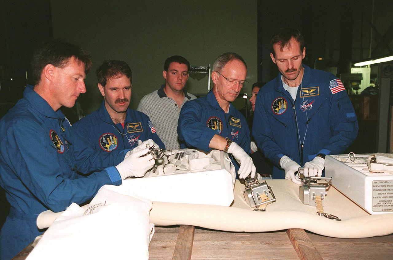 In the Orbiter Processing Facility (OPF) bay 1, STS-103 crew members check out equipment to be used on planned Extravehicular Activities (EVAs) on the mission for repair of the Hubble Space Telescope. They are taking part in a Crew Equipment Interface Test (CEIT) at KSC. From left are Mission Specialists C. Michael Foale (Ph.D.), John M. Grunsfeld (Ph.D.), Claude Nicollier of Switzerland, and Steven L. Smith. Other crew members at KSC for the CEIT are Commander Curtis L. Brown Jr., Pilot Scott J. Kelly, and Jean-François Clervoy of France. Nicollier and Clervoy are with the European Space Agency. Mission STS-103 is a "call-up" due to the need to replace portions of the pointing system, the gyros, which have begun to fail on the Hubble Space Telescope. Although Hubble is operating normally and conducting its scientific observations, only three of its six gyroscopes are working properly. The gyroscopes allow the telescope to point at stars, galaxies and planets. The STS-103 crew will not only replace gyroscopes, it will also replace a Fine Guidance Sensor and an older computer with a new enhanced model, an older data tape recorder with a solid-state digital recorder, a failed spare transmitter with a new one, and degraded insulation on the telescope with new thermal insulation. The crew will also install a Battery Voltage/Temperature Improvement Kit to protect the spacecraft batteries from overcharging and overheating when the telescope goes into a safe mode. The scheduled launch date in October is under review