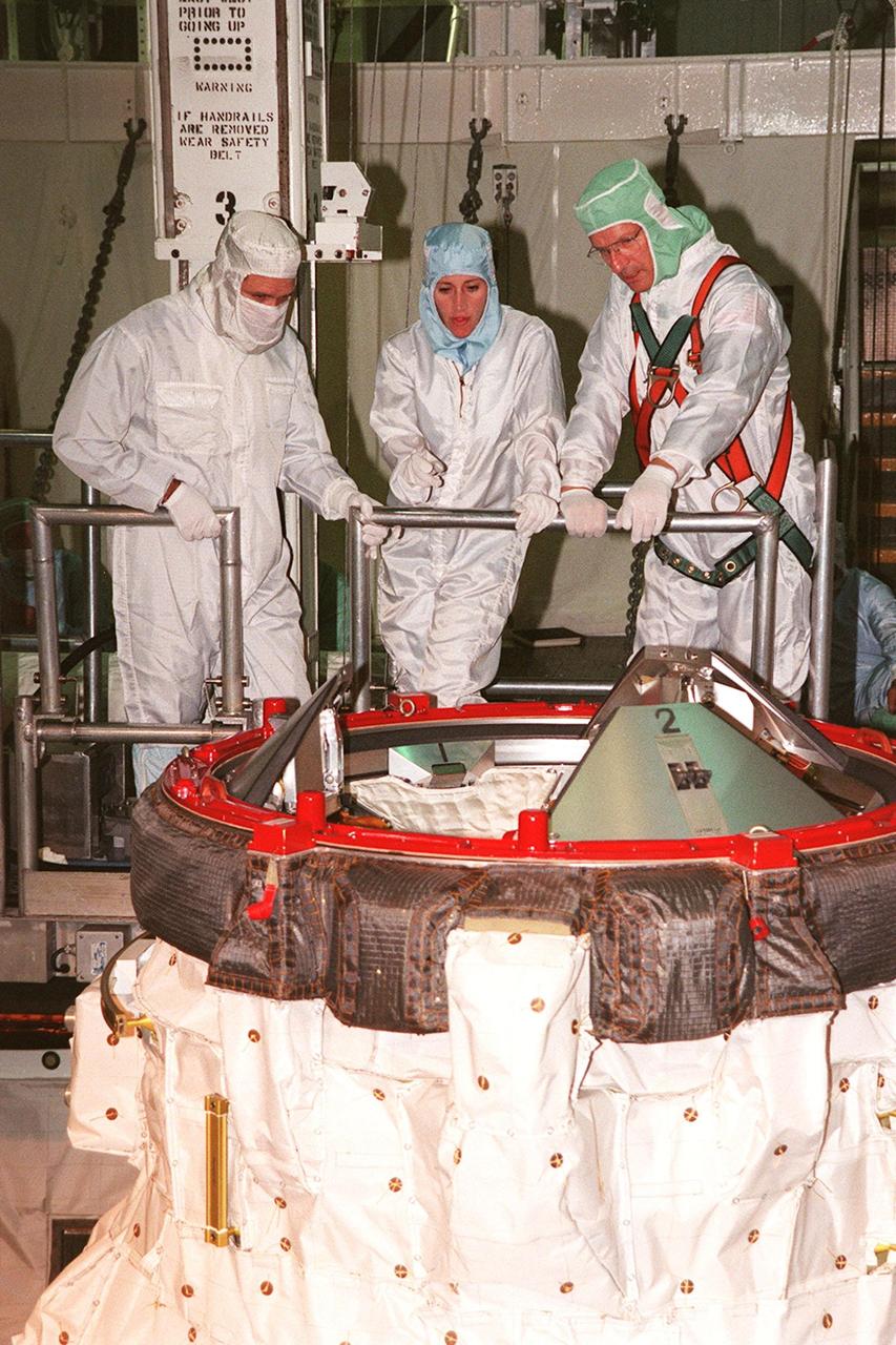 In the payload bay of the orbiter Discovery, STS-103 Mission Specialists John M. Grunsfeld (Ph.D.), left, and Claude Nicollier of Switzerland, right, are briefed on part of the equipment they will use on their mission by a worker from Johnson Space Center, center. The mission involves the repair and upgrade of the Hubble Space Telescope. The crew, who are at KSC to take part in a Crew Equipment Interface Test, also includes Commander Curtis L. Brown Jr., Pilot Scott J. Kelly, and Mission Specialists Steven L. Smith, C. Michael Foale (Ph.D.), and Jean-François Clervoy of France. Nicollier and Clervoy are with the European Space Agency. Mission STS-103 is a "call-up" due to the need to replace portions of the pointing system, the gyros, which have begun to fail on the Hubble Space Telescope. Although Hubble is operating normally and conducting its scientific observations, only three of its six gyroscopes are working properly. The gyroscopes allow the telescope to point at stars, galaxies and planets. The STS-103 crew will not only replace gyroscopes, it will also replace a Fine Guidance Sensor and an older computer with a new enhanced model, an older data tape recorder with a solid-state digital recorder, a failed spare transmitter with a new one, and degraded insulation on the telescope with new thermal insulation. The crew will also install a Battery Voltage/Temperature Improvement Kit to protect the spacecraft batteries from overcharging and overheating when the telescope goes into a safe mode. The scheduled launch date in October is under review