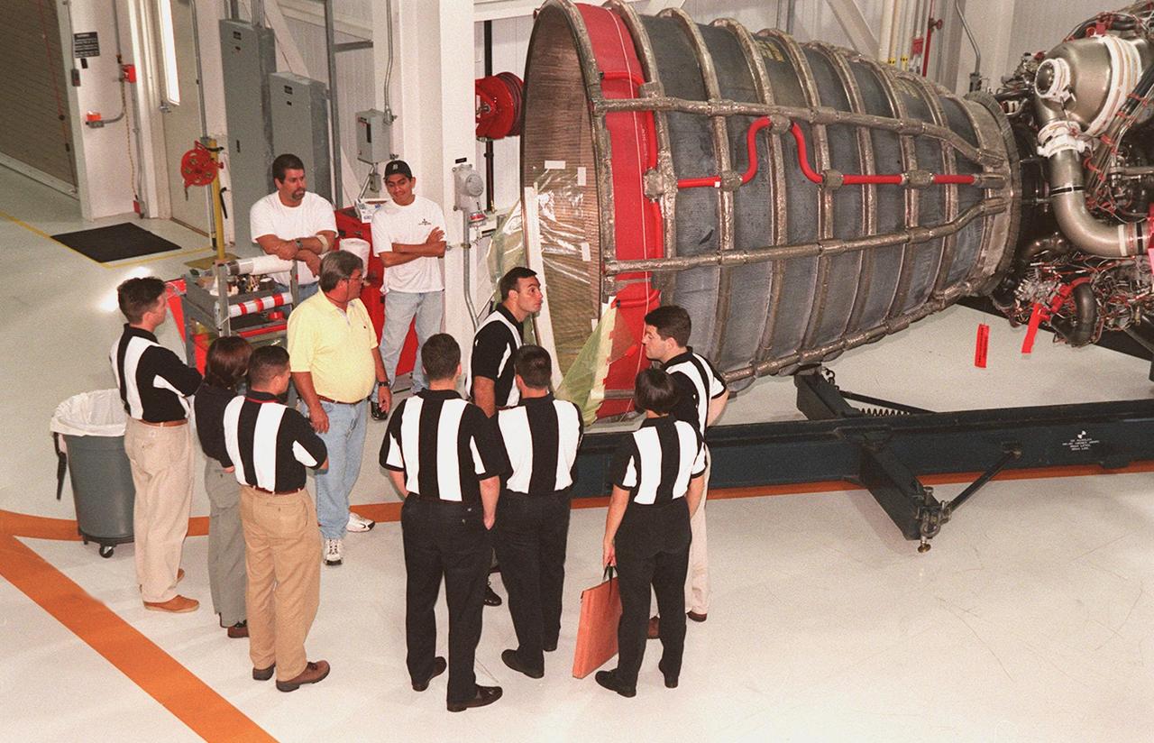 Members of the 1998 astronaut candidate class (group 17) look at the aft of a Space Shuttle Main Engine (SSME) (right). The class is at KSC for training activities, including fire training and a flight awareness program, plus touring the OPF, VAB, SSPF, launch pads, SLF, Apollo/Saturn V Center, the crew headquarters, as well as the SSME Processing Facility. The U.S. candidates in the '98 class are Clayton C. Anderson, Lee J. Archambault, Tracy E. Caldwell (Ph.D.), Gregory E. Chamitoff (Ph.D.), Timothy J. Creamer, Christopher J. Ferguson, Michael J. Foreman, Michael E. Fossum, Kenneth T. Ham, Patricia C. Hilliard (M.D.), Gregory C. Johnson, Gregory H. Johnson, Stanley G. Love (Ph.D.), Leland D. Melvin, Barbara R. Morgan, William A. Oefelein, John D. Olivas (Ph.D.), Nicholas J.M. Patrick (Ph.D.), Alan G. Poindexter, Garrett E. Reisman (Ph.D.), Steven R. Swanson, Douglas H. Wheelock, Sunita L. Williams, Neil W. Woodward III, George D. Zamka; and the international candidates are Leopold Eyharts, Paolo Nespoli, Hans Schlegel, Roberto Vittori, Bjarni V. Tryggvason, and Marcos Pontes
