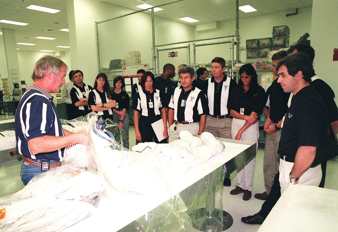 KENNEDY SPACE CENTER, FLA. -- In the Space Station Processing Facility, Ron Woods (left) shows members of the 1998 astronaut candidate class (group 17) an Apollo-style space suit and how it differs from the current suits. The class is taking part in training activities, including fire training and a flight awareness program, plus touring the OPF, VAB, SSPF, launch pads, SLF, Apollo/Saturn V Center, the crew headquarters, as well as the SSME Processing Facility. The U.S. candidates in the '98 class are Clayton C. Anderson, Lee J. Archambault, Tracy E. Caldwell (Ph.D.), Gregory E. Chamitoff (Ph.D.), Timothy J. Creamer, Christopher J. Ferguson, Michael J. Foreman, Michael E. Fossum, Kenneth T. Ham, Patricia C. Hilliard (M.D.), Gregory C. Johnson, Gregory H. Johnson, Stanley G. Love (Ph.D.), Leland D. Melvin, Barbara R. Morgan, William A. Oefelein, John D. Olivas (Ph.D.), Nicholas J.M. Patrick (Ph.D.), Alan G. Poindexter, Garrett E. Reisman (Ph.D.), Steven R. Swanson, Douglas H. Wheelock, Sunita L. Williams, Neil W. Woodward III, George D. Zamka; and the international candidates are Leopold Eyharts, Paolo Nespoli, Hans Schlegel, Roberto Vittori, Bjarni V. Tryggvason, and Marcos Pontes