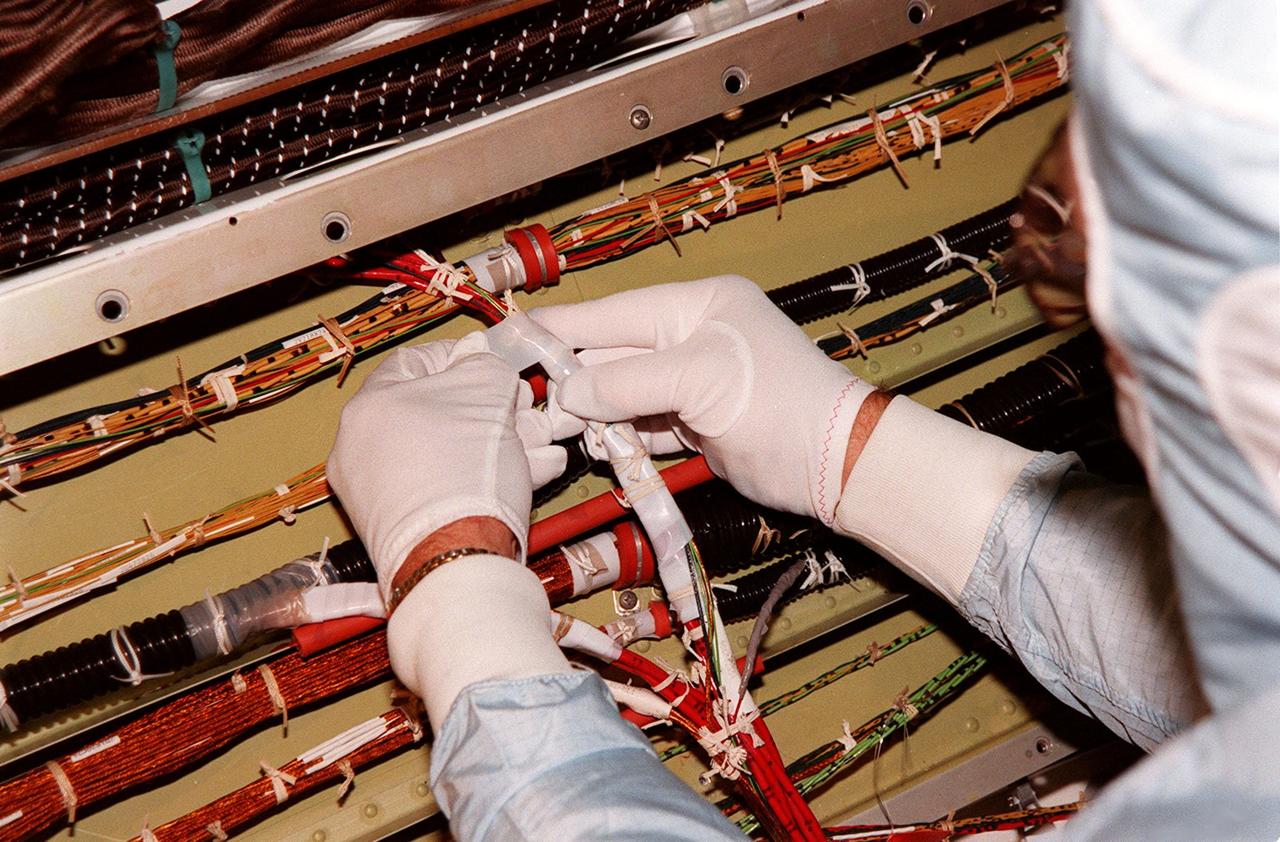 A short during liftoff of Space Shuttle Columbia in July was traced to a wire in the payload bay with damaged insulation. As a result of that problem, NASA decided to inspect much of the wiring in all four Space Shuttles and make repairs as required. Here a technician is protecting the wires onboard orbiter Discovery. The next Shuttle mission, STS-103, the Third Hubble Space Telescope Servicing Mission, is currently scheduled for launch no earlier than Nov. 19, 1999