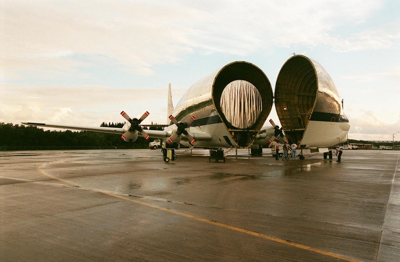 KENNEDY SPACE CENTER, FLA. -- At KSC's Shuttle Landing Facility, NASA's Super Guppy opens to reveal its cargo, the International Space Station's (ISS) S1 truss. Manufactured by the Boeing Co. in Huntington Beach, Calif., this component of the ISS is the first starboard (right-side) truss segment, whose main job is providing structural support for the orbiting research facility's radiator panels that cool the Space Station's complex power system. The S1 truss segment also will house communications systems, external experiment positions and other subsystems. Primarily constructed of aluminum, the truss segment is 45 feet long, 15 feet wide and 6 feet tall. When fully outfitted, it will weigh 31,137 pounds. The truss is slated for flight in 2001. The Super Guppy, with its 25-foot diameter fuselage designed to handle oversized loads, is well prepared to transport the truss and other ISS segments. Loading the Guppy is easy because of the unique "fold-away" nose of the aircraft that opens 110 degrees for cargo loading. A system of rails in the cargo compartment, used with either Guppy pallets or fixtures designed for specific cargo, makes cargo loading simple and efficient. Rollers mounted in the rails allow pallets or fixtures to be moved by an electric winch mounted beneath the cargo floor. Automatic hydraulic lock pins in each rail secure the pallet for flight. The truss is to be transferred to the Operations and Checkout Building
