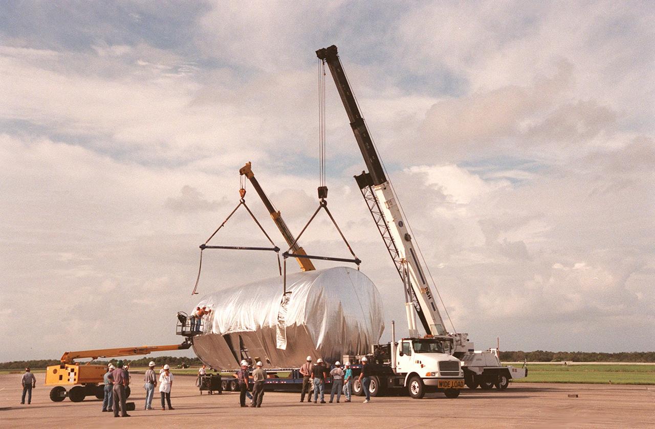 KENNEDY SPACE CENTER, FLA. -- At the Shuttle Landing Facility, workers attach cranes to the S1 truss, a segment of the International Space Station, to lift the truss to a payload transporter for its transfer to the Operations and Checkout Building. Manufactured by the Boeing Co. in Huntington Beach, Calif., this component of the ISS is the first starboard (right-side) truss segment, whose main job is providing structural support for the orbiting research facility's radiator panels that cool the Space Station's complex power system. The S1 truss segment also will house communications systems, external experiment positions and other subsystems. Primarily constructed of aluminum, the truss segment is 45 feet long, 15 feet wide and 6 feet tall. When fully outfitted, it will weigh 31,137 pounds. The truss is slated for flight in 2001. The truss arrived at KSC aboard NASA's Super Guppy, with a 25-foot diameter fuselage designed to handle oversized loads. Loading the Guppy is easy because of the unique "fold-away" nose of the aircraft that opens 110 degrees for cargo loading. A system of rails in the cargo compartment, used with either Guppy pallets or fixtures designed for specific cargo, makes cargo loading simple and efficient. Rollers mounted in the rails allow pallets or fixtures to be moved by an electric winch mounted beneath the cargo floor. Automatic hydraulic lock pins in each rail secure the pallet for flight