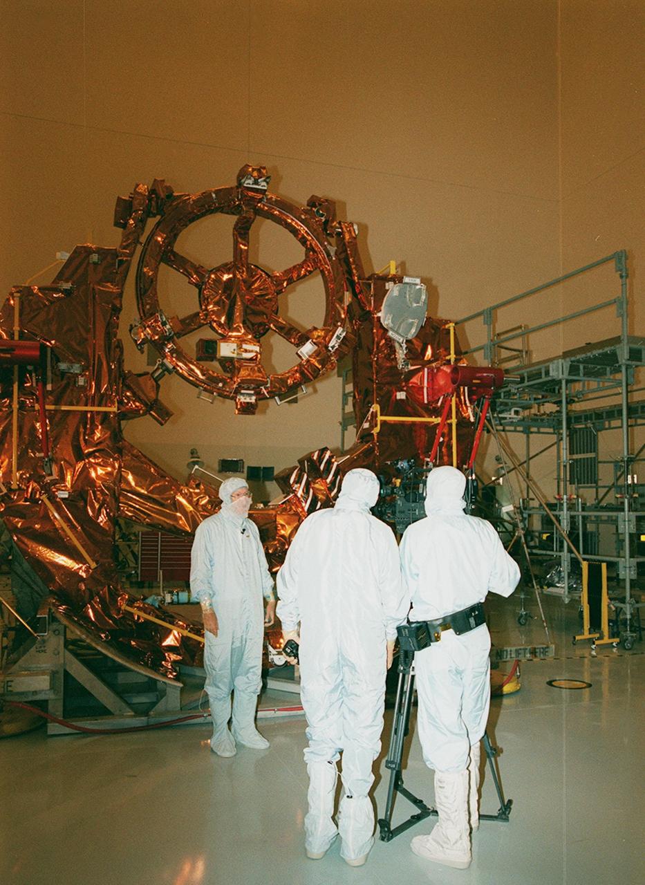 KENNEDY SPACE CENTER, FLA. -- In the Payload Hazardous Servicing Facility clean room, part of the flight hardware for the Hubble Space Telescope Servicing mission is on display for media representatives. Dr. John Campbell, associate director, Hubble Space Telescope, provides commentary for a video being recorded for NASA by videographer Glen Benson (right). Between them is George Diller, public information officer for KSC. This mission is designed to replace aging parts on the nine-year-old observatory and to upgrade some of its functioning systems. During the flight, the astronaut crew will replace all six of Hubble's gyroscopes, a fine guidance sensor, the observatory's main computer, and other equipment. The 10-day mission is scheduled to launch no earlier than Dec. 2 at 4:32 a.m. EST from Launch Complex 39