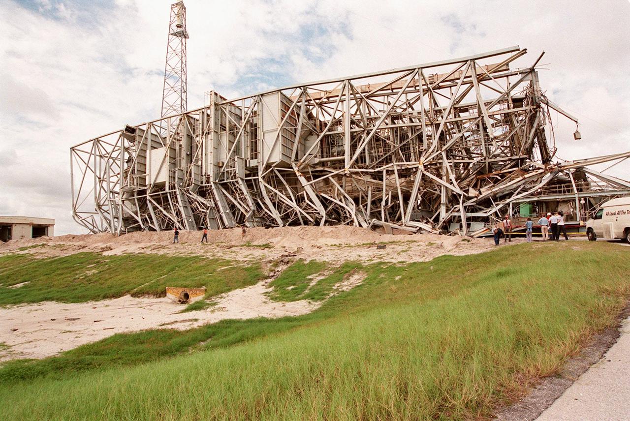 KENNEDY SPACE CENTER, FLA. -- The 300-foot, five-million-pound Mobile Service Tower (MST) on Launch Complex 41, Cape Canaveral Air Force Station, lies on its side after being demolished. The MST and a 200-foot-high umbilical tower nearby were demolished to make room for Lockheed Martin's 14-acre Vehicle Integration Facility (VIF), under construction. Only lightning protection towers, such as the one seen behind the MST, remain standing at the site. About 200 pounds of linear-shaped charges were used to bring down the towers so that the materials can be recycled. The implosion and removal of the tower debris is expected to be completed in two months. The VIF will be used for Lockheed Martin's Atlas V Launch System.