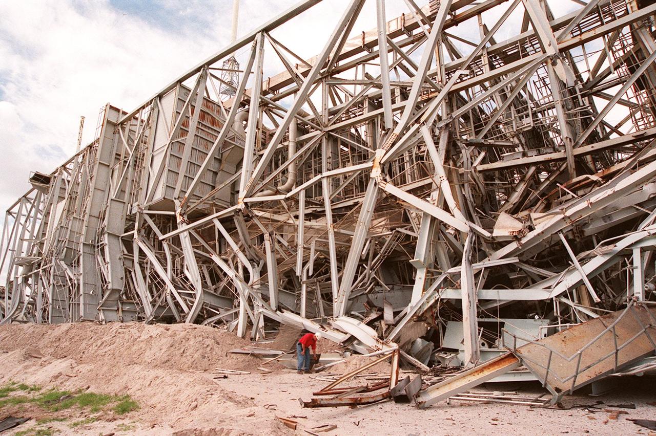 KENNEDY SPACE CENTER, FLA. -- Workers are dwarfed by the fallen 300-foot, five-million-pound Mobile Service Tower (MST) on Launch Complex 41, Cape Canaveral Air Force Station.  The MST and a 200-foot-high umbilical tower nearby were demolished to make room for Lockheed Martin's 14-acre Vehicle Integration Facility (VIF), under construction.  Only lightning protection towers remain standing at the site.  About 200 pounds of linear-shaped charges were used to bring down the towers so that the materials can be recycled.  The implosion and removal of the tower debris is expected to be completed in two months.  The VIF will be used for Lockheed Martin's Atlas V Launch System.
