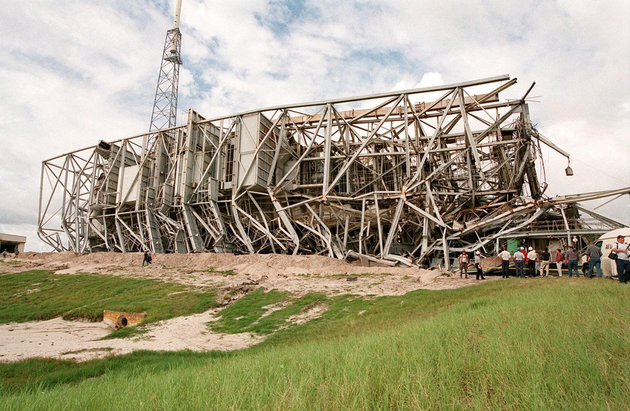 KENNEDY SPACE CENTER, FLA. -- The fallen 300-foot, five-million-pound Mobile Service Tower (MST) on Launch Complex 41, Cape Canaveral Air Force Station, looms over the head of a worker on the ground beside it. The MST and a 200-foot-high umbilical tower nearby were demolished to make room for Lockheed Martin's 14-acre Vehicle Integration Facility (VIF), under construction. Only lightning protection towers, such as the one seen behind the MST, remain standing at the site. About 200 pounds of linear-shaped charges were used to bring down the towers so that the materials can be recycled. The implosion and removal of the tower debris is expected to be completed in two months. The VIF will be used for Lockheed Martin's Atlas V Launch System.