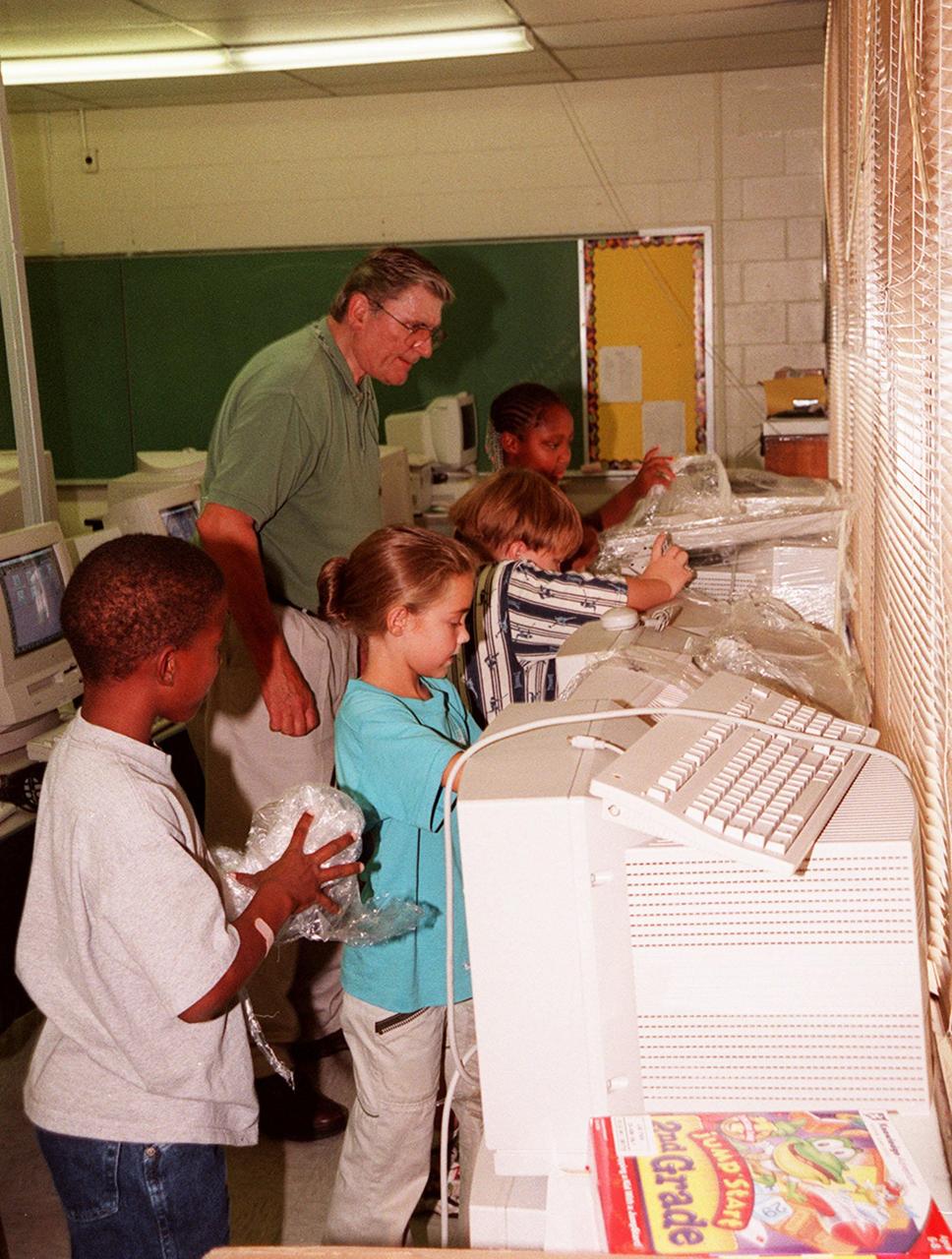 Children at Cambridge Elementary School, Cocoa, Fla., eagerly unwrap computer equipment donated by Kennedy Space Center. Cambridge is one of 13 Brevard County schools receiving 81 excess contractor computers thanks to an innovative educational outreach project spearheaded by the Nasa k-12 Education Services Office at ksc. Behind the children is Jim Thurston, a school volunteer and retired employee of USBI, who shared in the project. The Astronaut Memorial Foundation, a strategic partner in the effort, and several schools in rural Florida and Georgia also received refurbished computers as part of the year-long project. KSC employees put in about 3,300 volunteer hours to transform old, excess computers into upgraded, usable units. A total of $90,000 in upgraded computer equipment is being donated