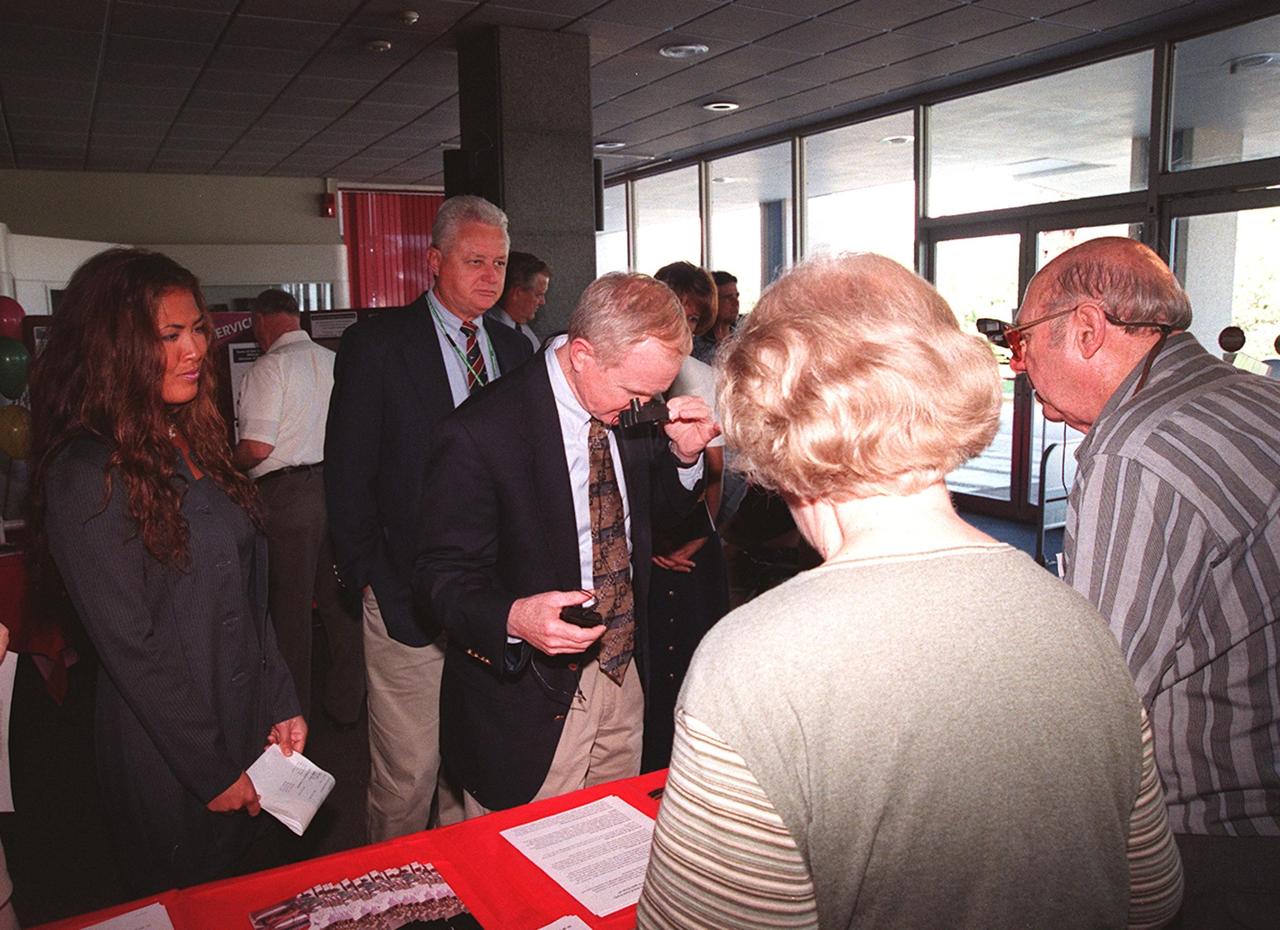 Center Director Roy Bridges stops at the Stewart Eye Institute table at the Disability Awareness and Action Working Group (DAAWG) 1999 Technology Fair being held Oct. 20-21 at Kennedy Space Center. Behind Bridges is Sterling Walker, director of Engineering Development at KSC and chairman of DAAWG. At the near right are George and Marian Hall, who are with the Institute. At the left is Nancie Strott, a multi-media specialist with Dynacs and chairperson of the Fair. The Fair is highlighting vendors demonstrating mobility, hearing, vision and silent disability assistive technology. The purpose is to create an awareness of the types of technology currently available to assist people with various disabilities in the workplace. The theme is that of this year's National Disability Employment Awareness Month, "Opening Doors to Ability." Some of the vendors participating are Canine Companions for Independence, Goodwill Industries, Accessible Structures, Division of Blind Services, Space Coast Center for Independent Living, KSC Fitness Center and Delaware North Parks Services