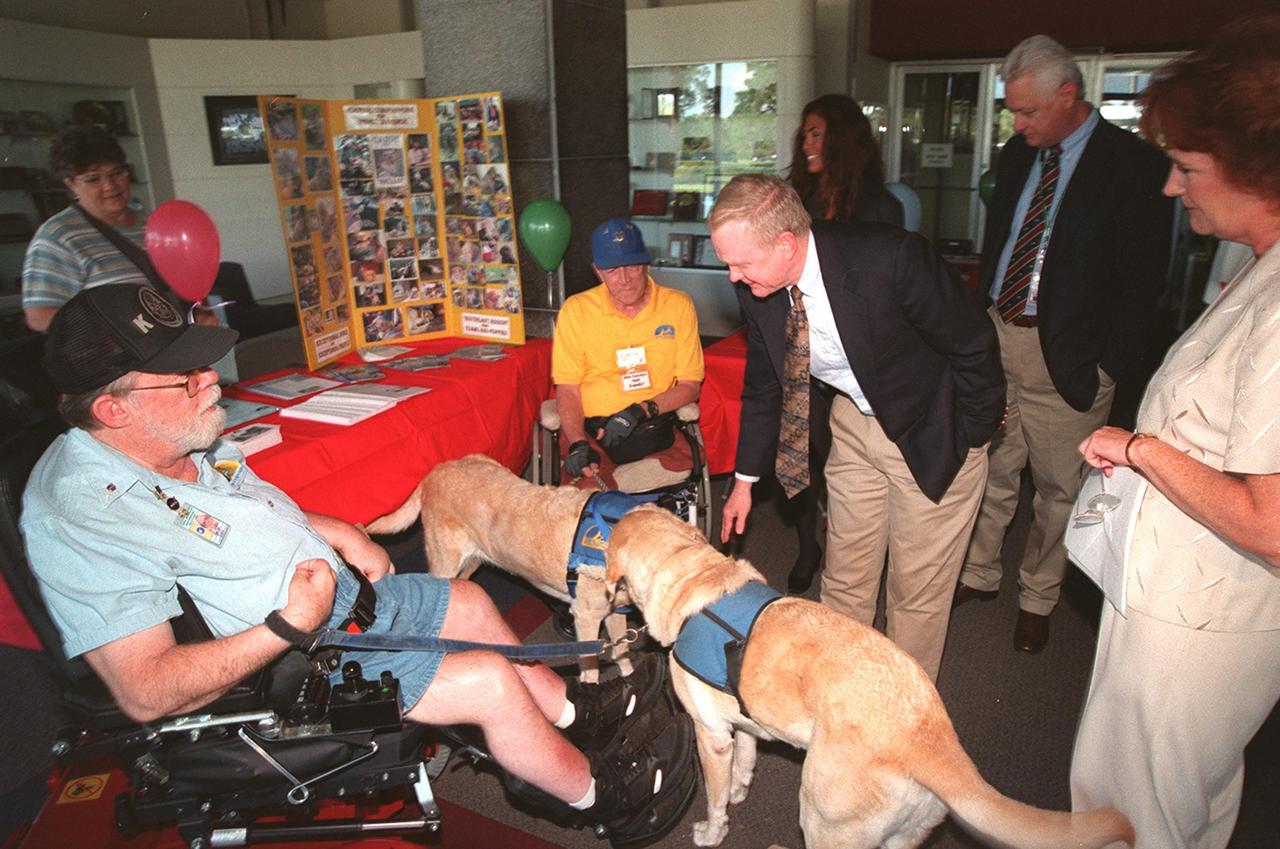 Center Director Roy Bridges stops to pet one of the dogs that serves with Canine Companions for Independence, a vendor displaying its capabilities at the Disability Awareness and Action Working Group (DAAWG) 1999 Technology Fair being held Oct. 20-21 at Kennedy Space Center. Standing at the right is Carol Cavanaugh, with KSC Public Services; behind Bridges is Nancie Strott (left), a multi-media specialist with Dynacs and chairperson of the Fair, and Sterling Walker (right), director of Engineering Development and chairman of DAAWG. The Fair is highlighting vendors demonstrating mobility, hearing, vision and silent disability assistive technology. The purpose is to create an awareness of the types of technology currently available to assist people with various disabilities in the workplace. The theme is that of this year's National Disability Employment Awareness Month, "Opening Doors to Ability." Some of the other vendors participating are Goodwill Industries, Accessible Structures, Division of Blind Services, Space Coast Center for Independent Living, KSC Fitness Center and Delaware North Parks Services