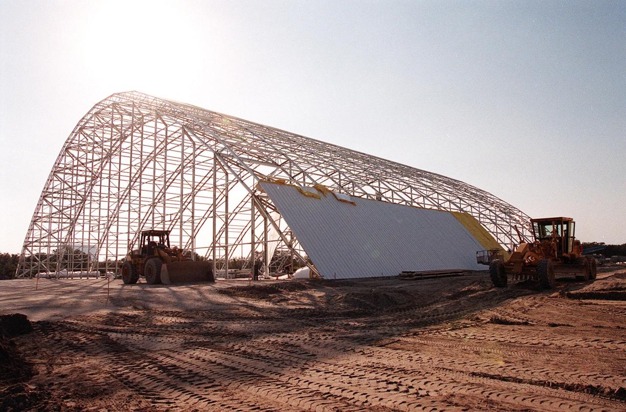 The first roof panels are placed on the multi-purpose hangar at the site of the $8 million Reusable Launch Vehicle (RLV) Support Complex at Kennedy Space Center. The RLV complex, which includes the hangar and a building for related ground support equipment and administrative/technical support, will be available to accommodate the Space Shuttle; the X-34 RLV technology demonstrator; the L-1011 carrier aircraft for Pegasus and X-34; and other RLV and X-vehicle programs. The complex is jointly funded by the Spaceport Florida Authority, NASA's Space Shuttle Program and KSC. The facility will be operational in early 2000